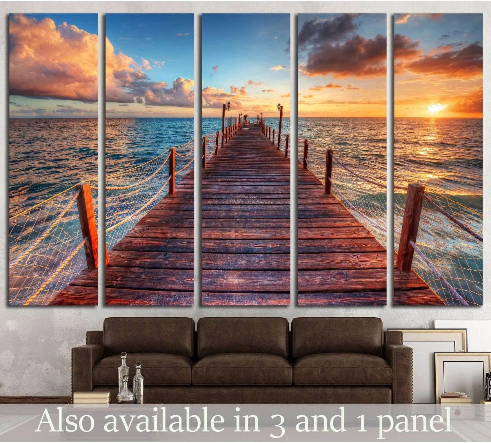 Sunrise pier canvas print with wooden dock, azure sea, and glowing clouds above a sofa