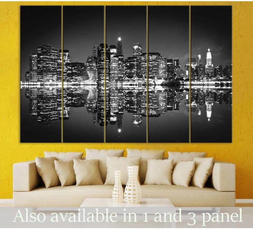 Black and white NYC skyline canvas print with mirrored reflection, displayed as five panels above a sofa in a modern living room
