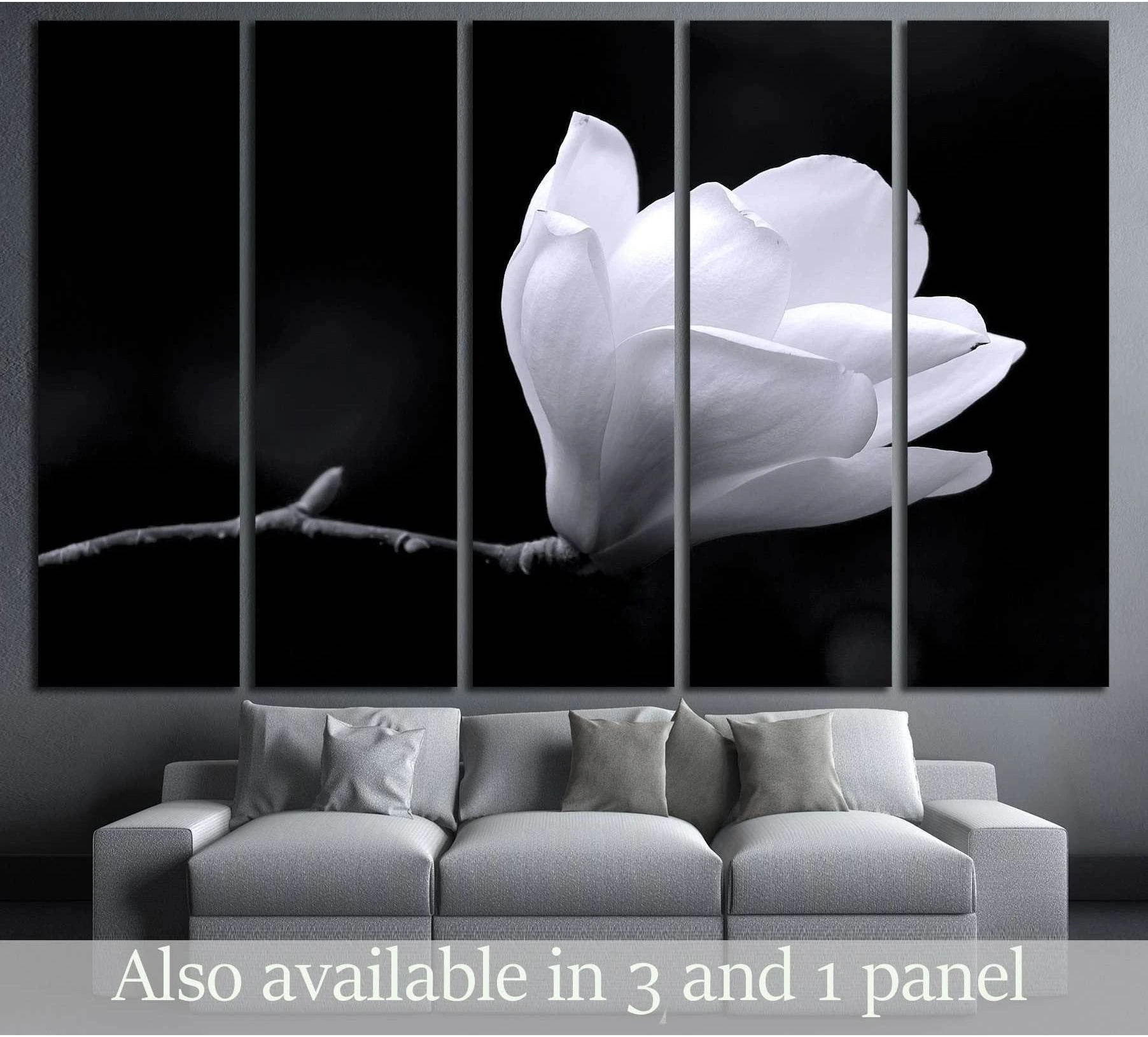 Black and white magnolia flower canvas print hung above sofa in a modern neutral living room