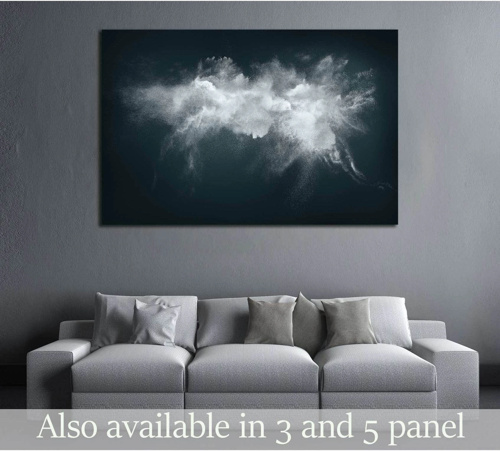 Abstract white powder cloud canvas print over a dark teal background, displayed above a gray sofa