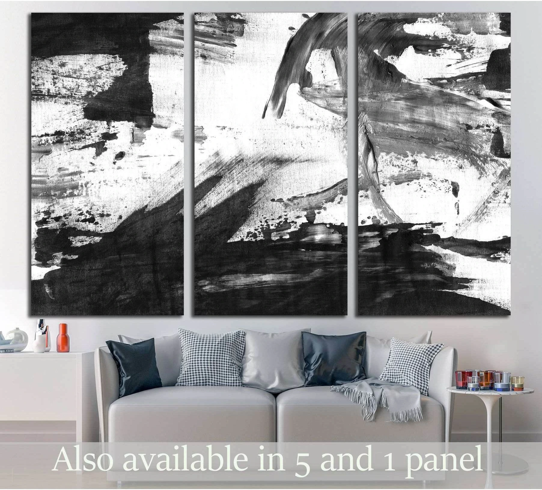 Black and white abstract triptych canvas print with bold ink brushstrokes above a modern sofa