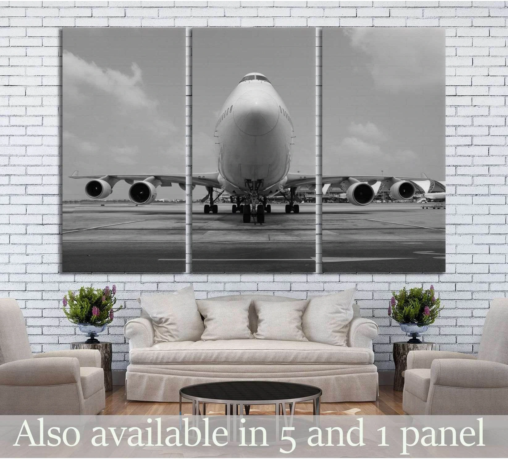 Black and white jumbo jet triptych canvas print with front-facing airplane on runway above a sofa