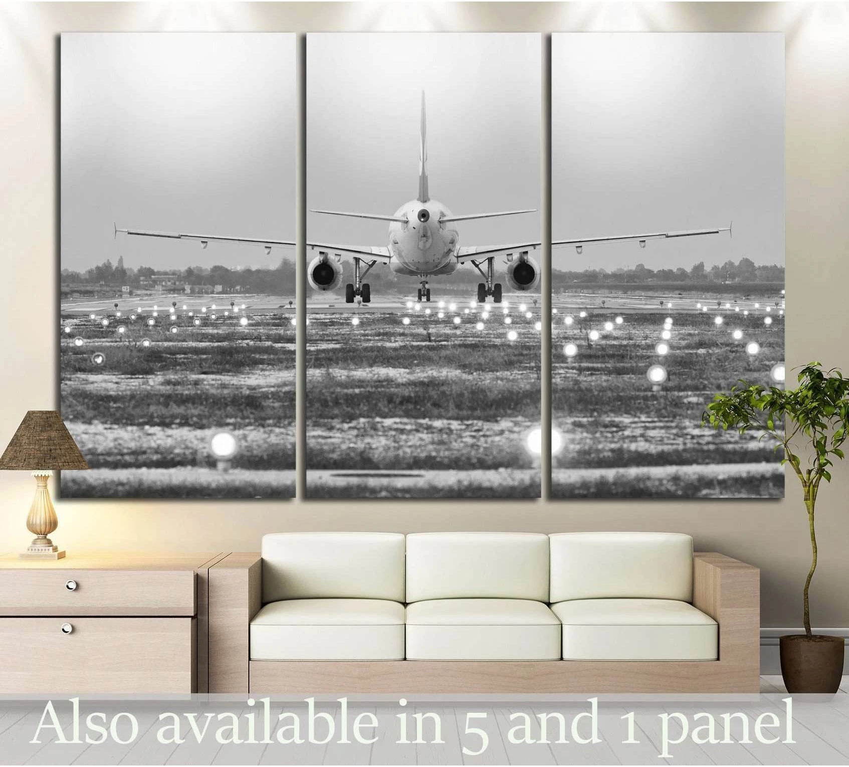 Black and white airplane runway canvas print in triptych layout hung above a sofa in a modern living room