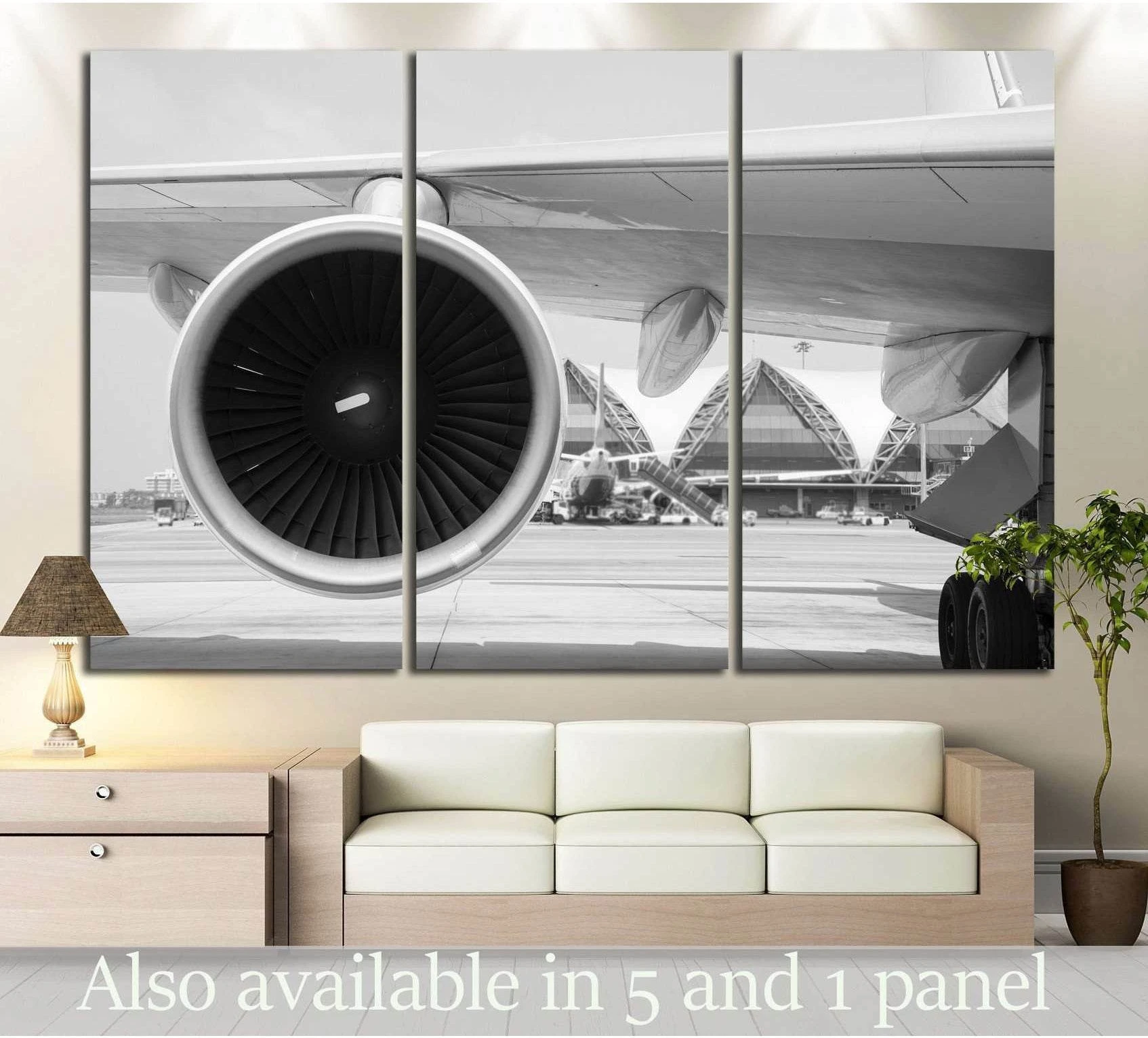 Black and white jet engine canvas print in triptych layout above sofa in a modern living room