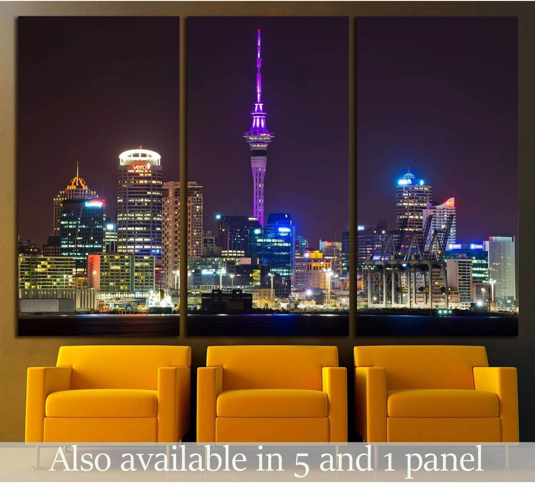 Auckland skyline triptych canvas print with Sky Tower lit purple at night, displayed above yellow chairs