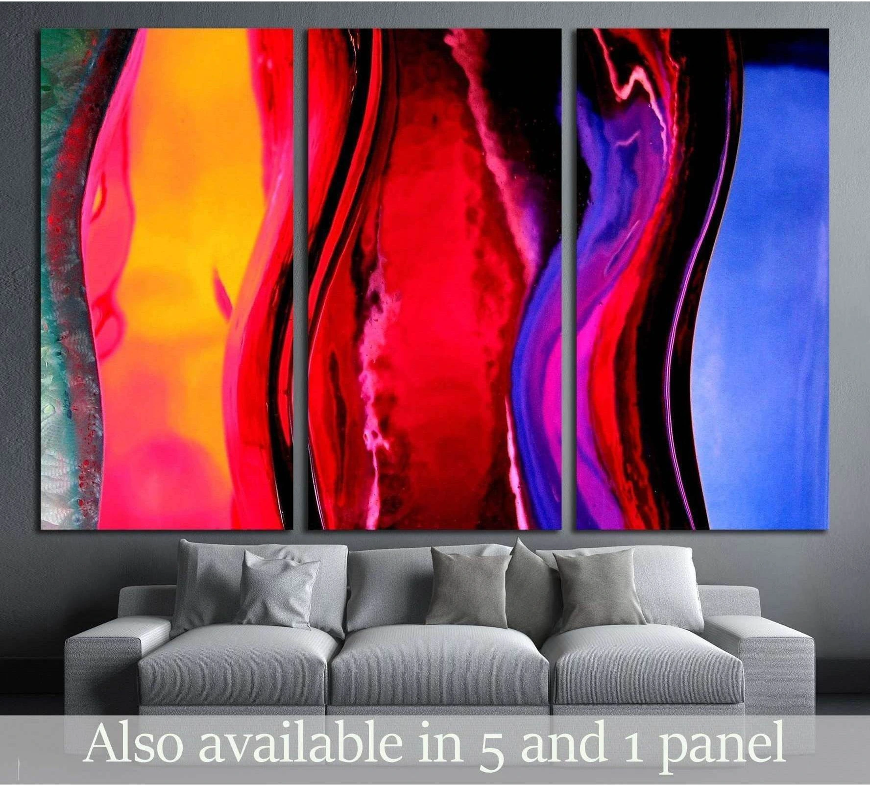 Abstract triptych canvas print with red, pink, orange, purple, and blue fluid forms above a gray sofa
