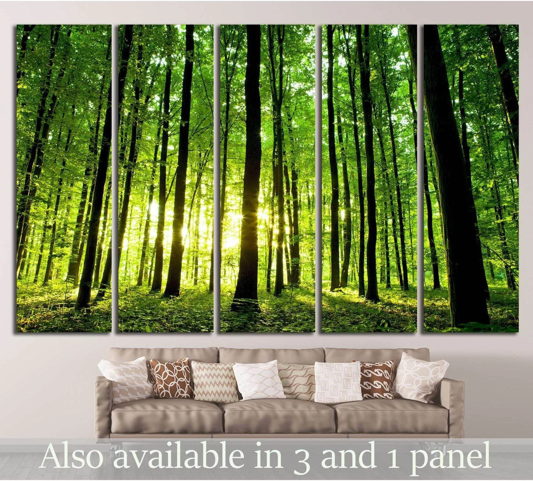Sunlit green forest canvas print with tall woodland trees above a sofa in a neutral living room