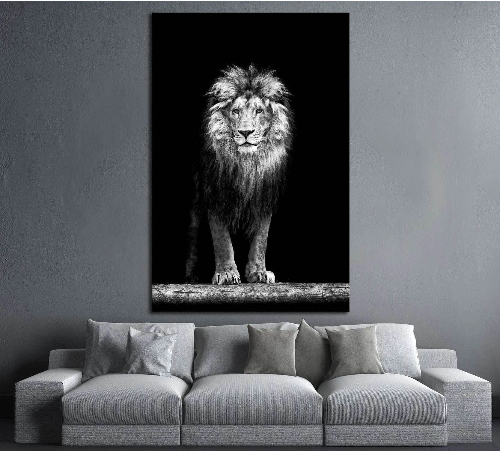 Black and white lion canvas print with full mane portrait on a dark background above a gray sofa