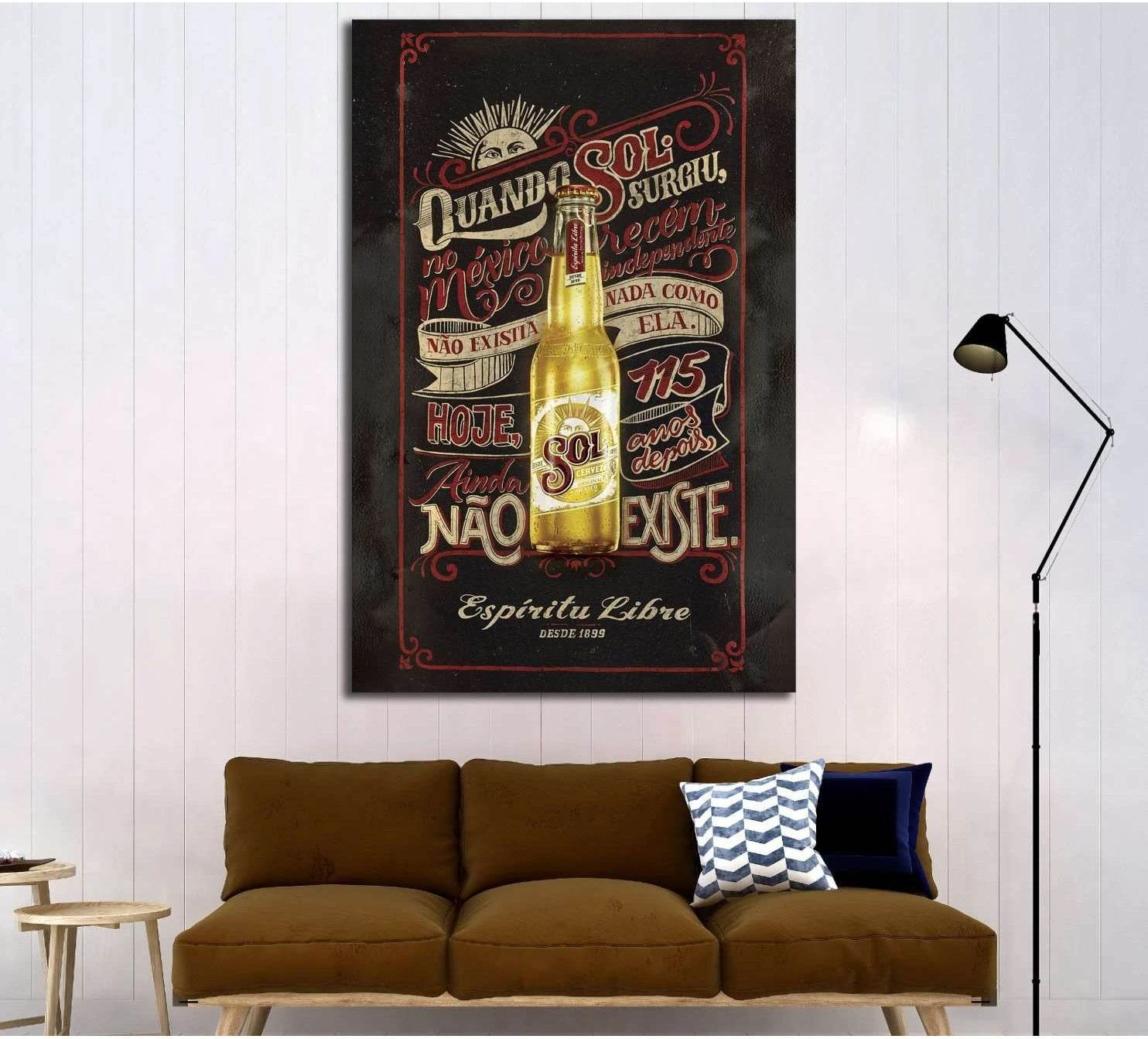 Vintage beer poster canvas print with amber bottle and retro lettering, displayed above a brown sofa in a modern living room