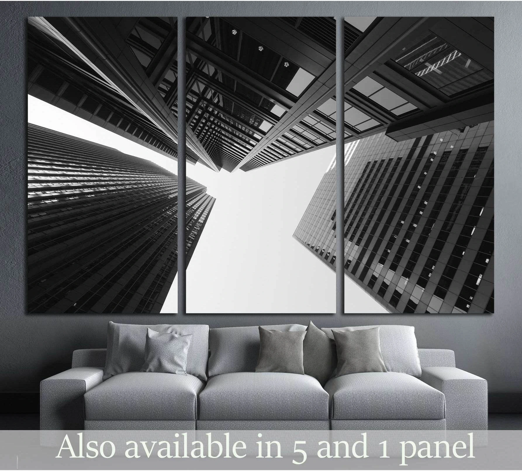 Black and white skyscraper canvas print in triptych layout above a sofa in a modern living room