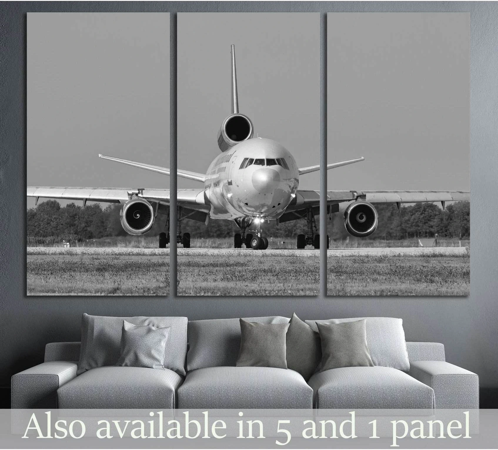 Black and white airplane triptych canvas print with front-view jet on the runway above a gray sofa