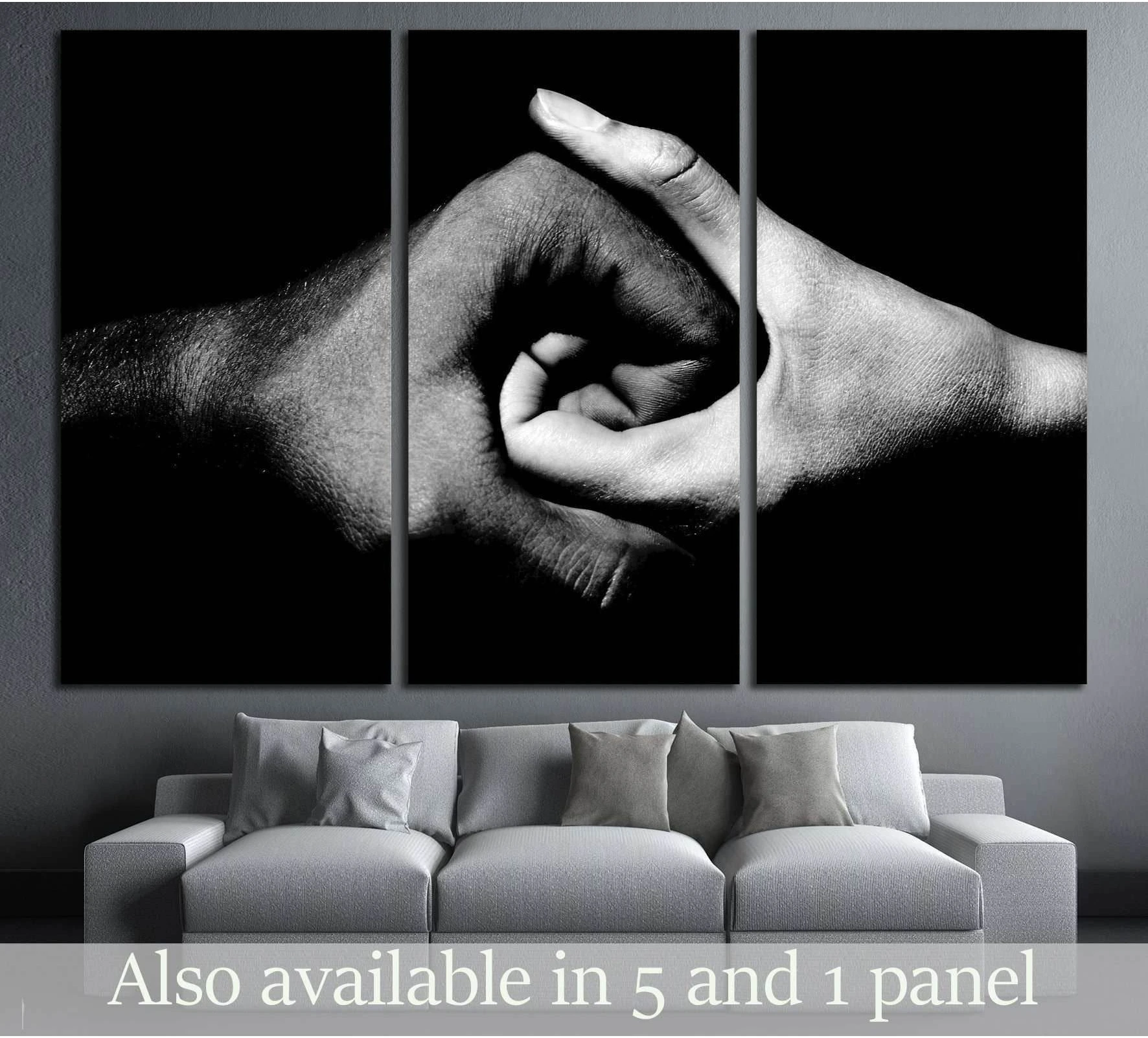 Black and white hands holding together triptych canvas print above a sofa in a modern grey living room