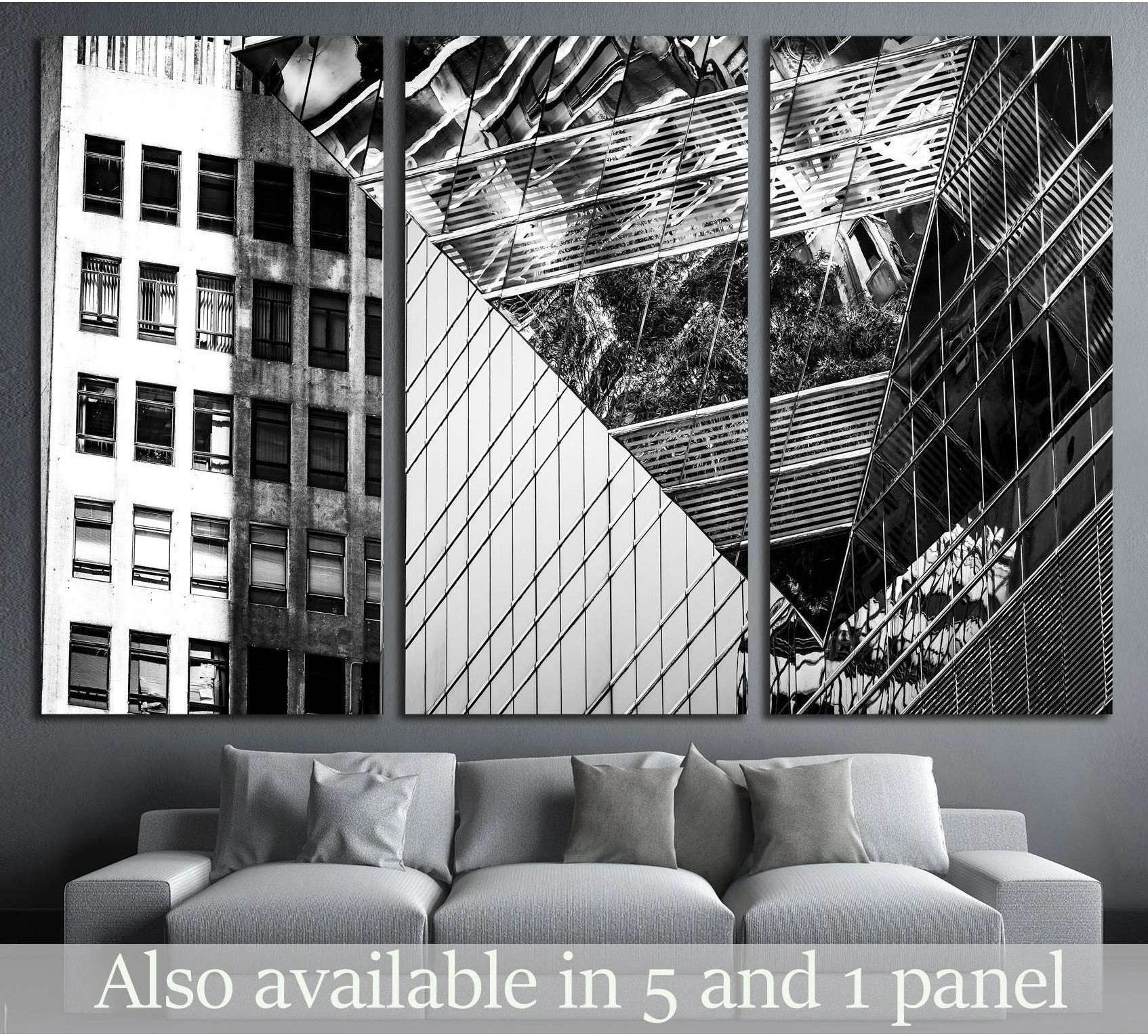 Black and white commercial buildings triptych canvas print above a sofa in a modern gray living room