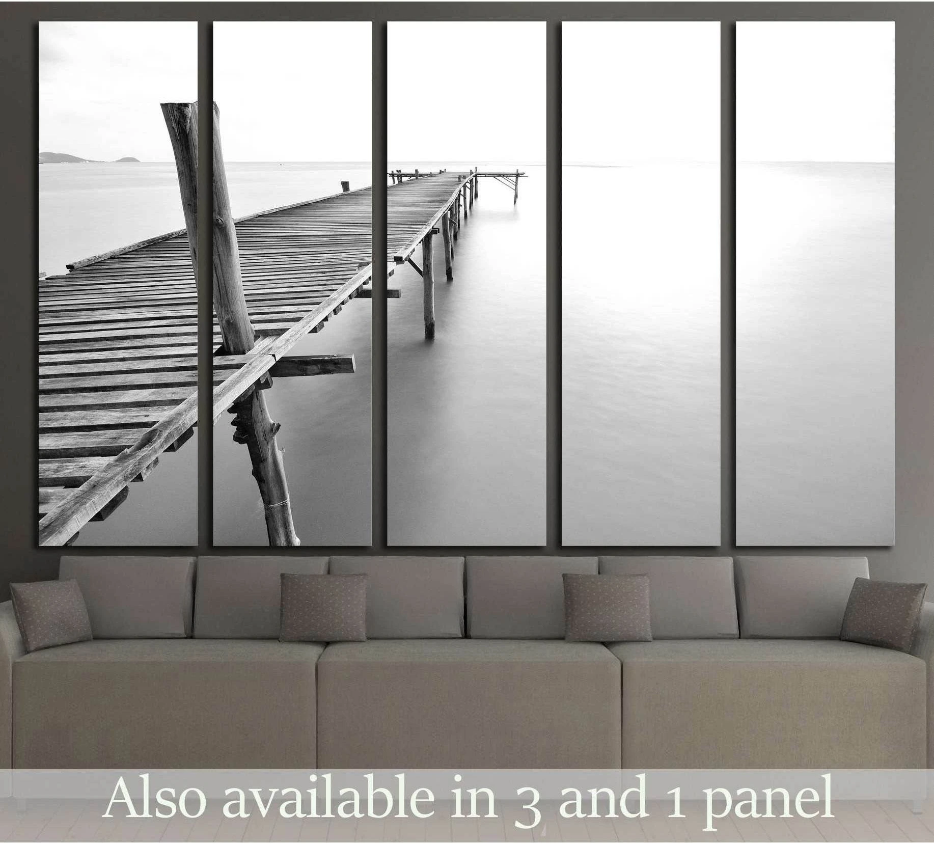 Black and white pier canvas print above sofa showing an old wooden jetty stretching into a calm sea