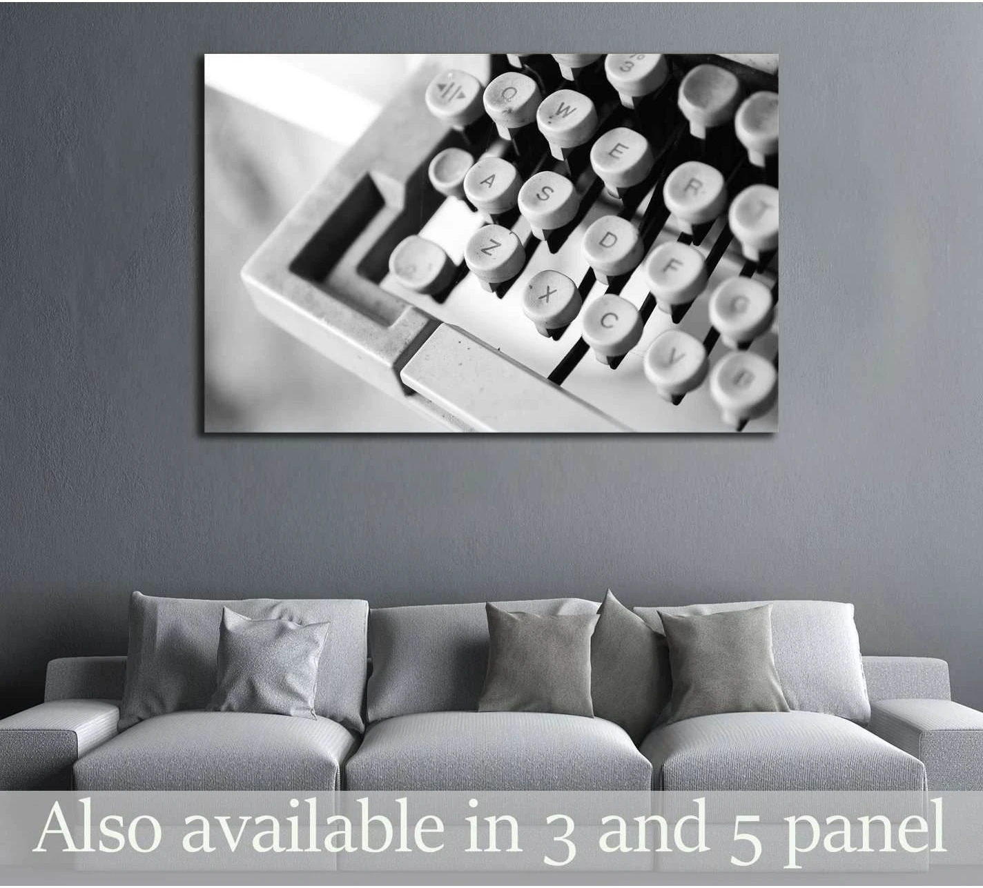 Black and white vintage typewriter keys canvas print hung above a gray sofa in a modern room