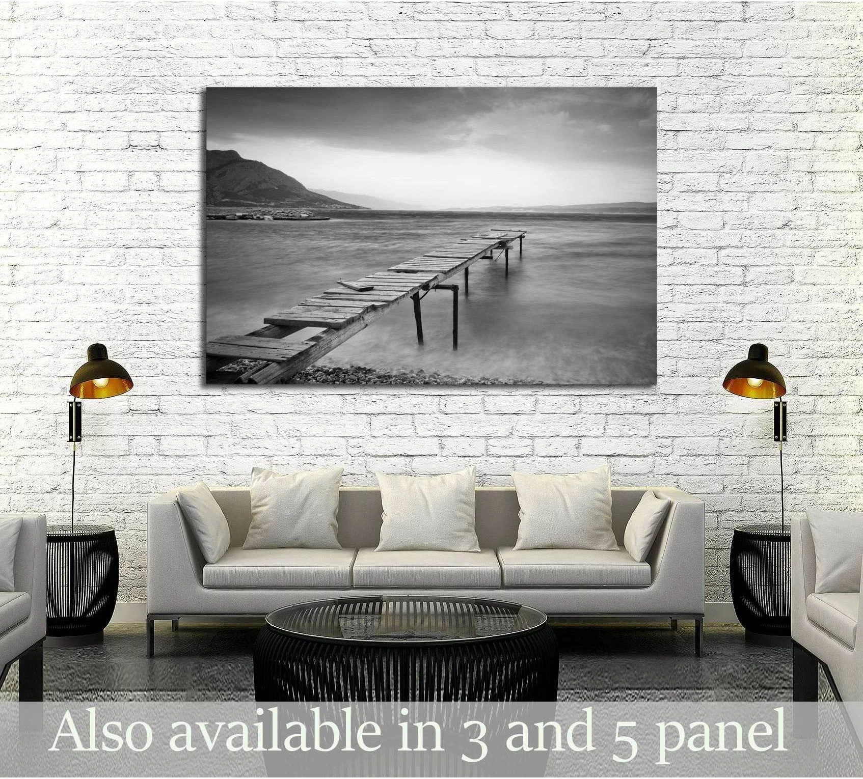 Black and white jetty canvas print over calm water above sofa in modern living room