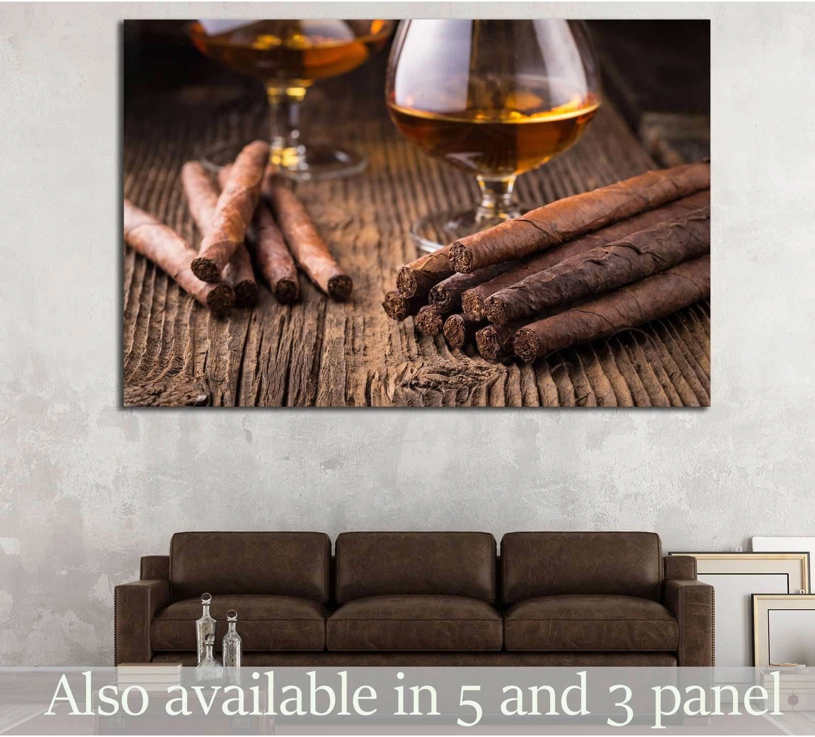 Cigar and whiskey canvas print with rolled cigars and amber liquor glasses above a brown sofa in a rustic living room
