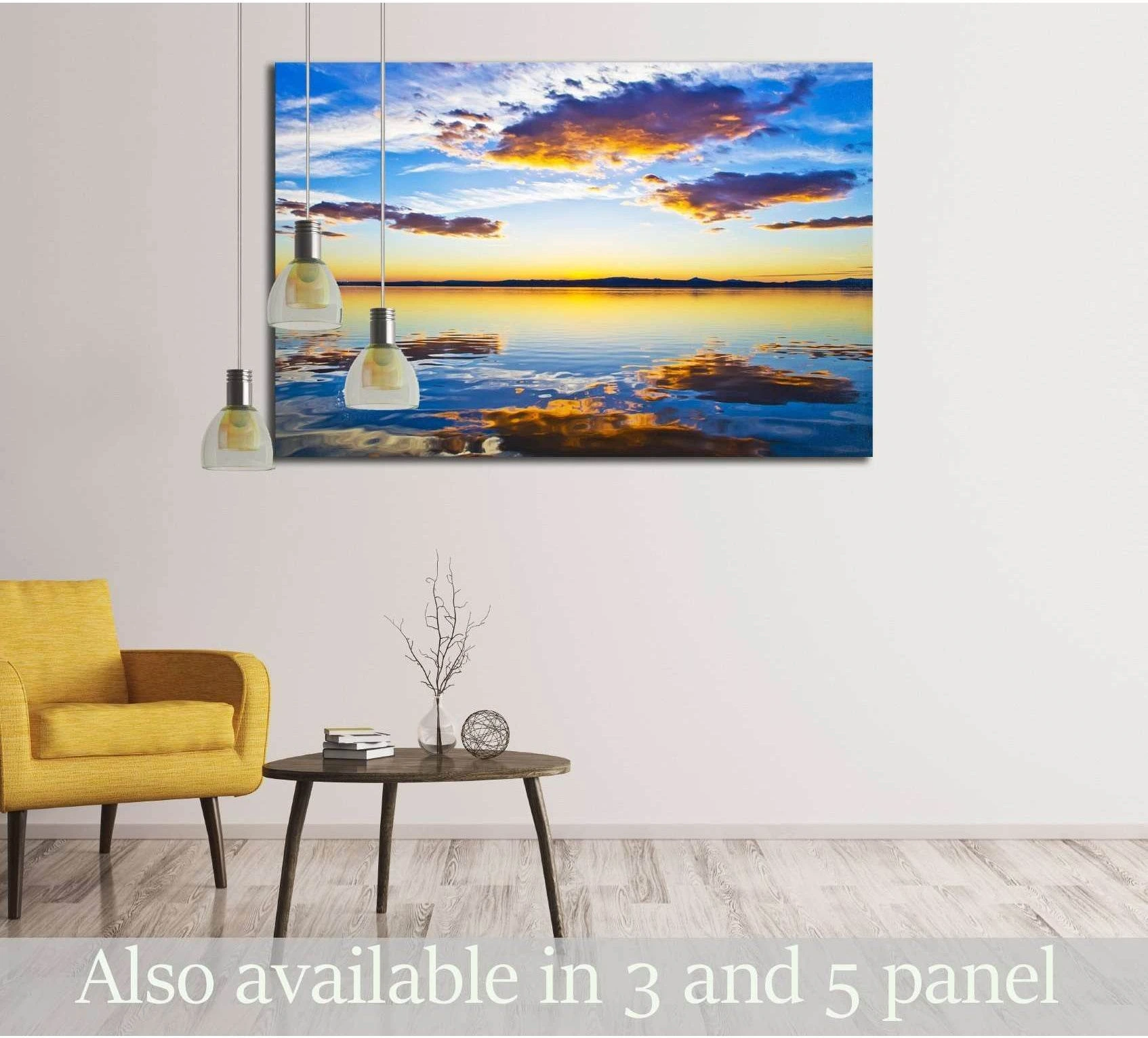Sunset lake canvas print with blue and gold clouds reflected on calm water above a chair in a modern living room