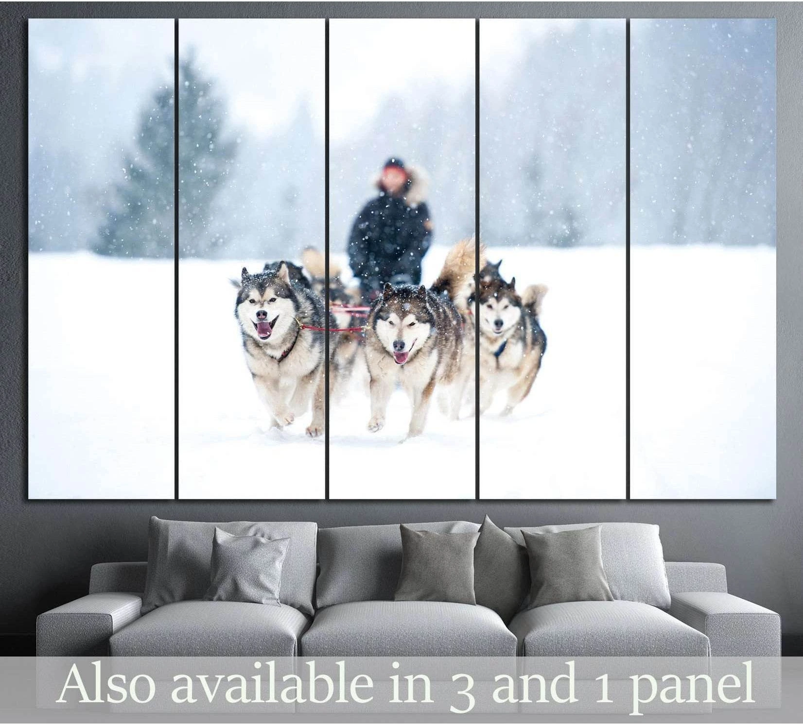 Husky sled team canvas print with running dogs in falling snow above a sofa in a modern living room