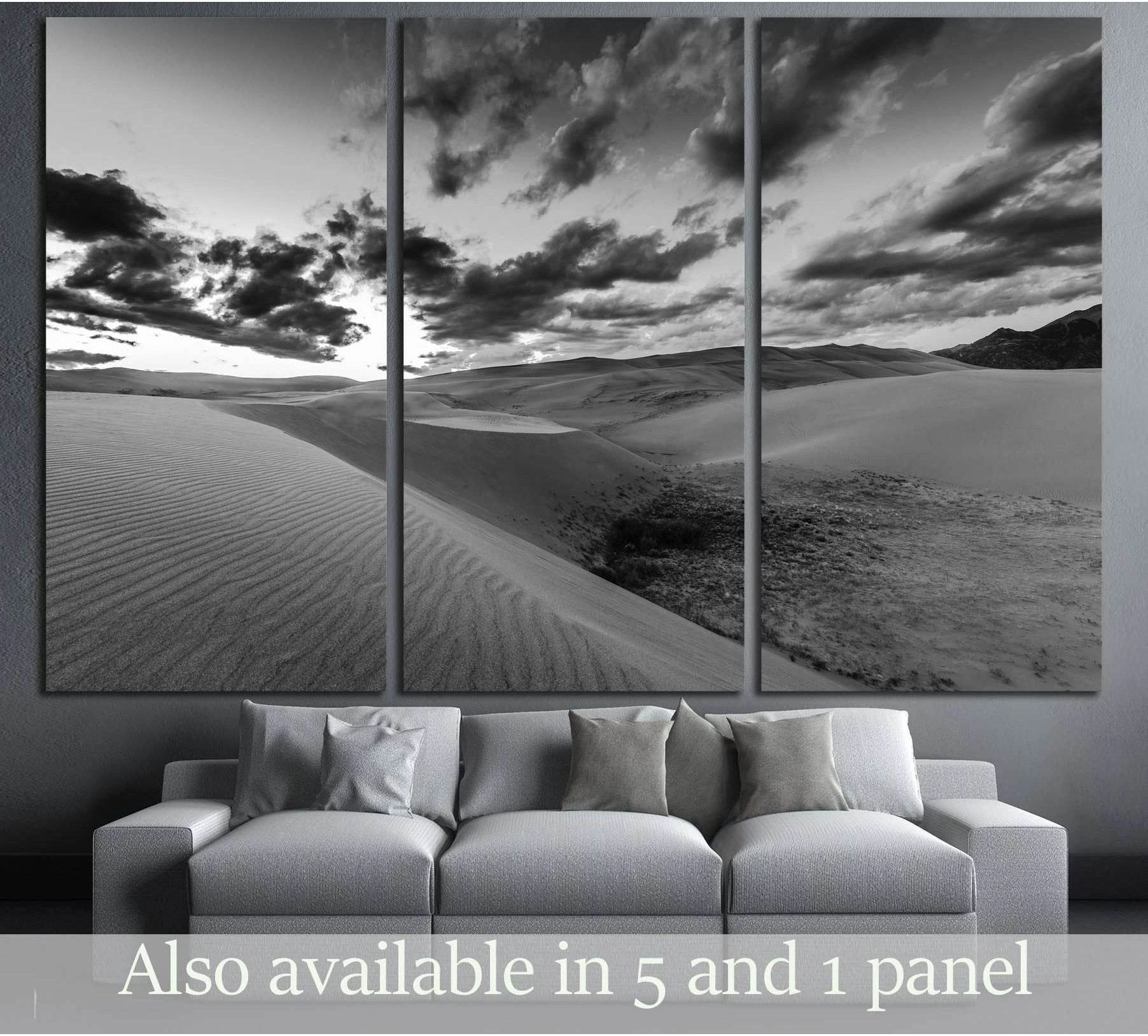 Black and white desert dunes canvas print with dramatic clouds above a sofa in a modern living room