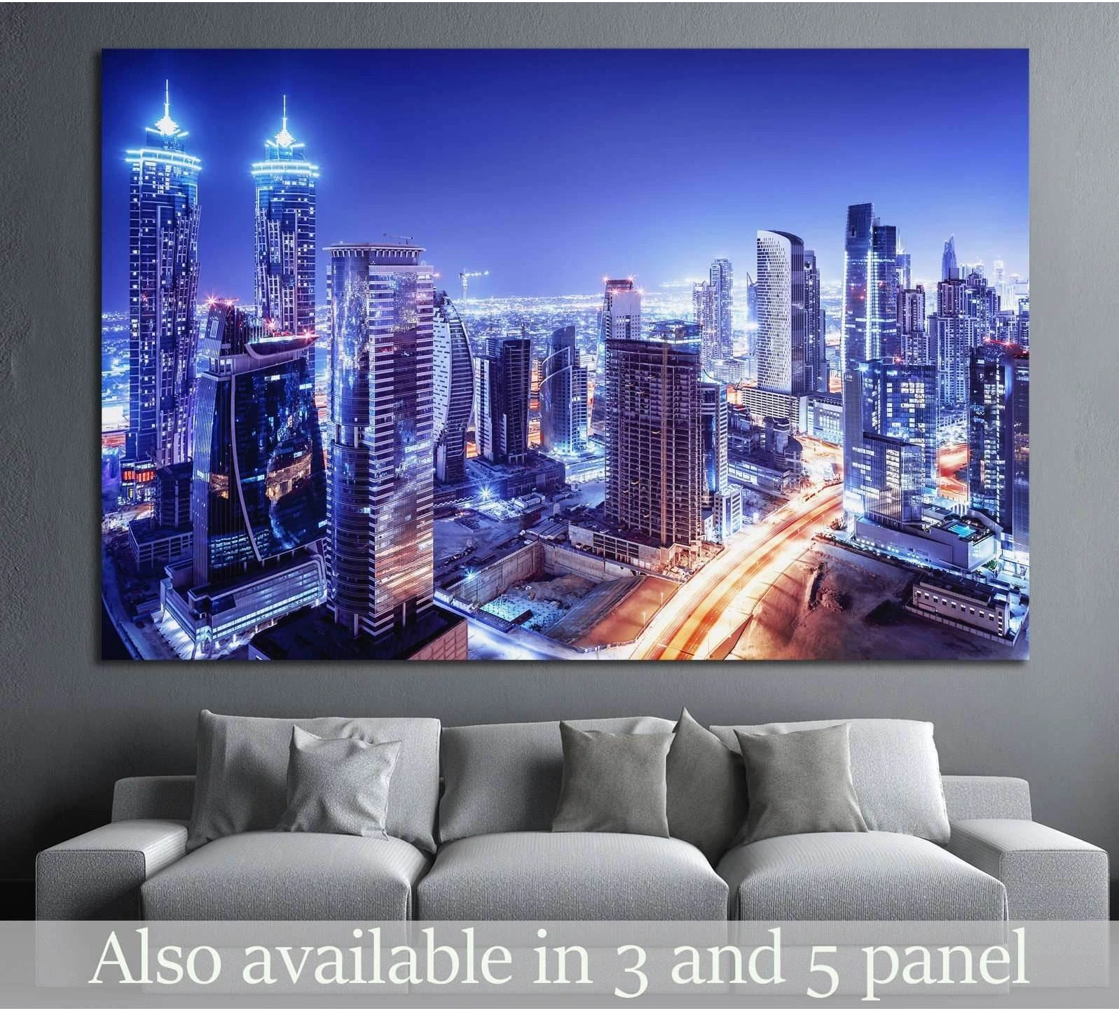 Dubai skyline canvas print with glowing blue towers above a gray sofa in a modern living room