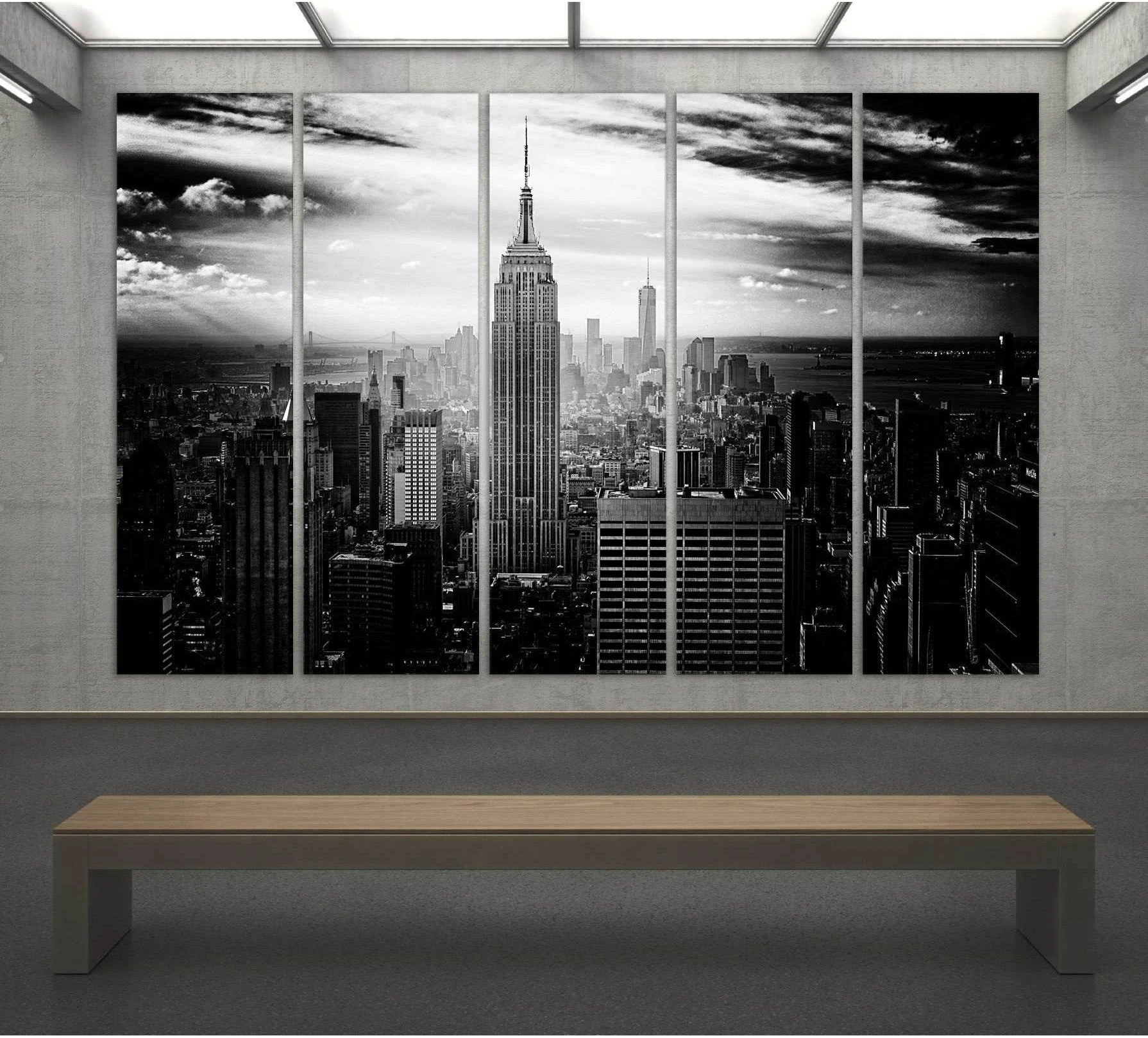 Black and white Empire State Building triptych canvas print above bench in a modern gallery-style room