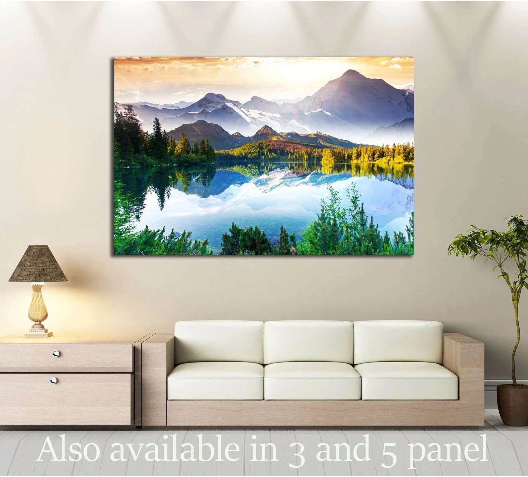 Mountain lake canvas print with alpine peaks and blue water reflection above a sofa in a neutral living room