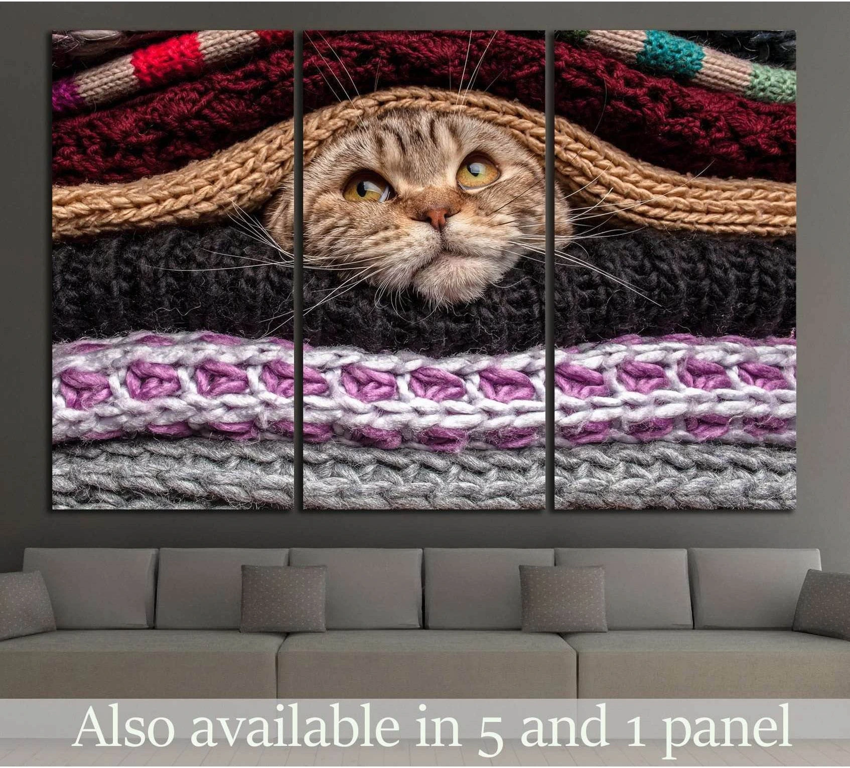 Tabby cat peeking through chunky knit blankets triptych canvas print above a sofa in a cozy living room