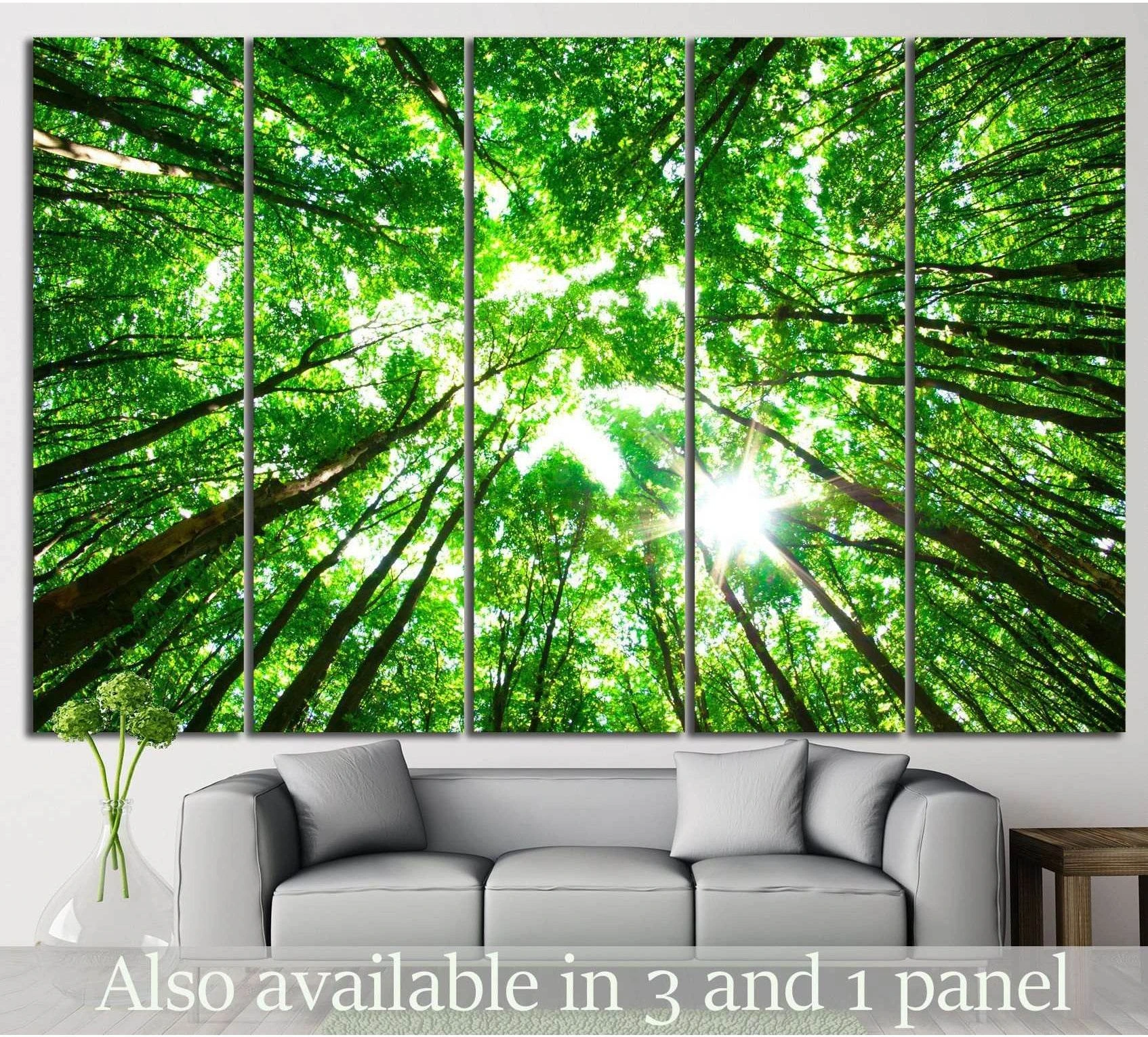 Sunlit green forest canopy canvas print with tall trees viewed from below, displayed above a sofa