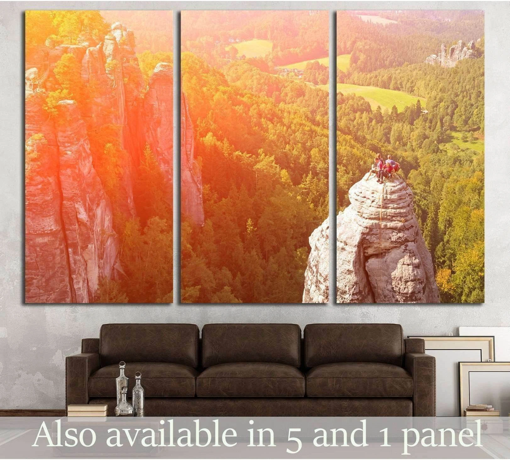 Rock climbers on a stone pinnacle above a forest valley triptych canvas print hung above a sofa