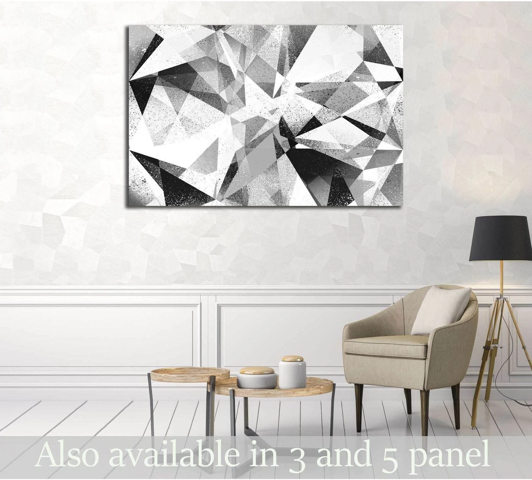 Black and white geometric canvas print with faceted abstract forms above a chair in a modern living room
