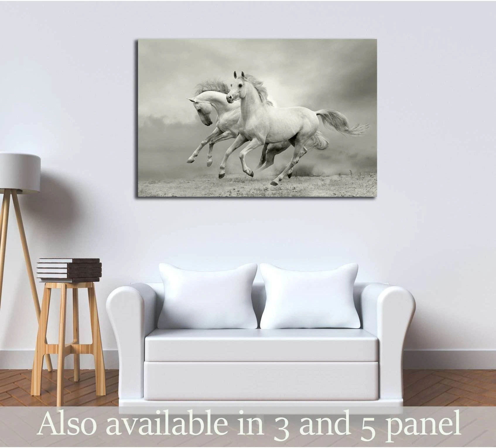 Two white horses galloping across a dusty field canvas print above a sofa in a neutral living room
