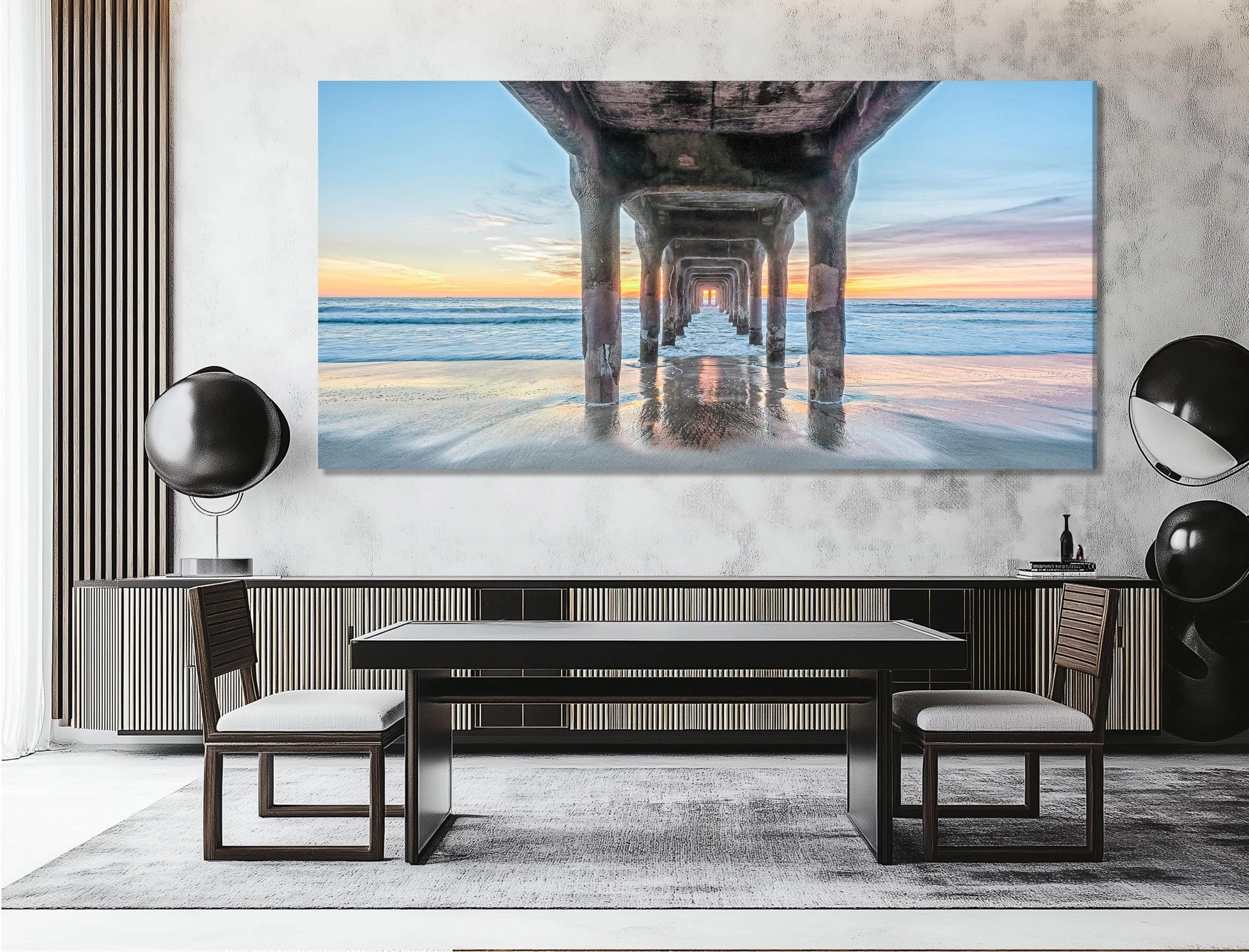 Sunset beach scene viewed under a pier, with reflective wet sand and ocean waves detail view