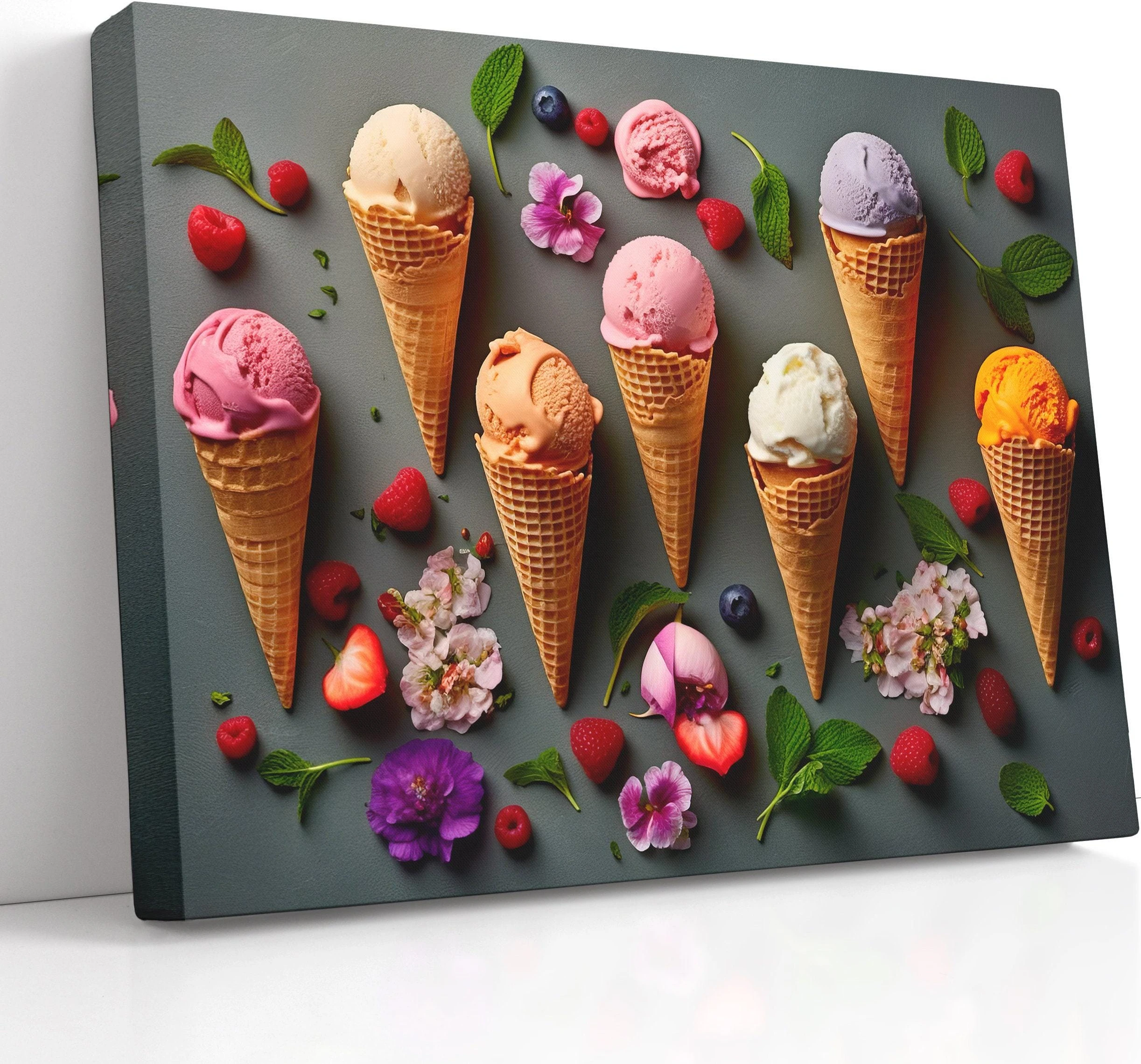 A colourful arrangement of ice-cream cones, scoops and berries sits on a dark grey background, surrounded by scattered flowers and mint leaves
