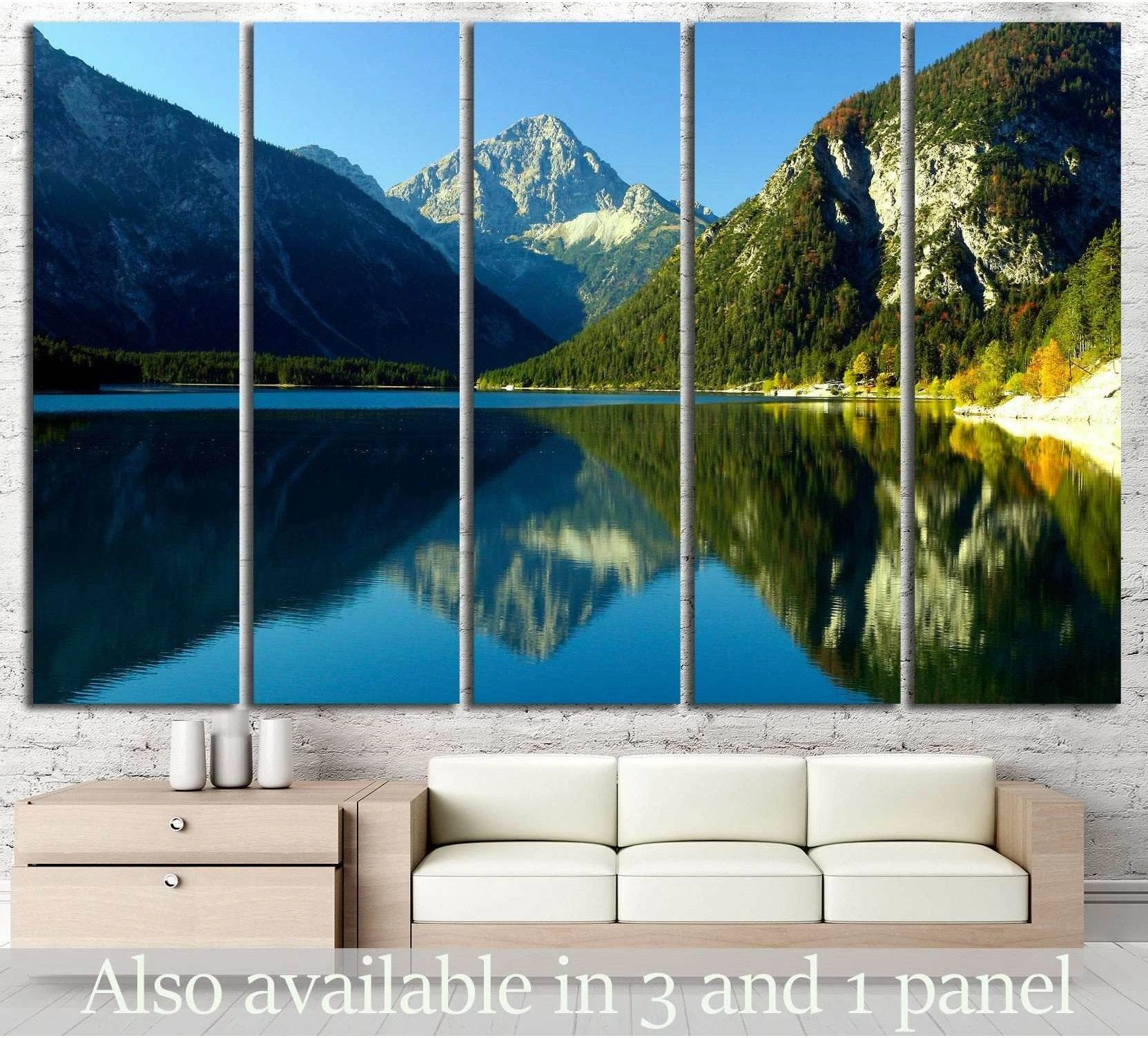 Alpine lake canvas print with mountain reflection shown above a sofa in a modern living room