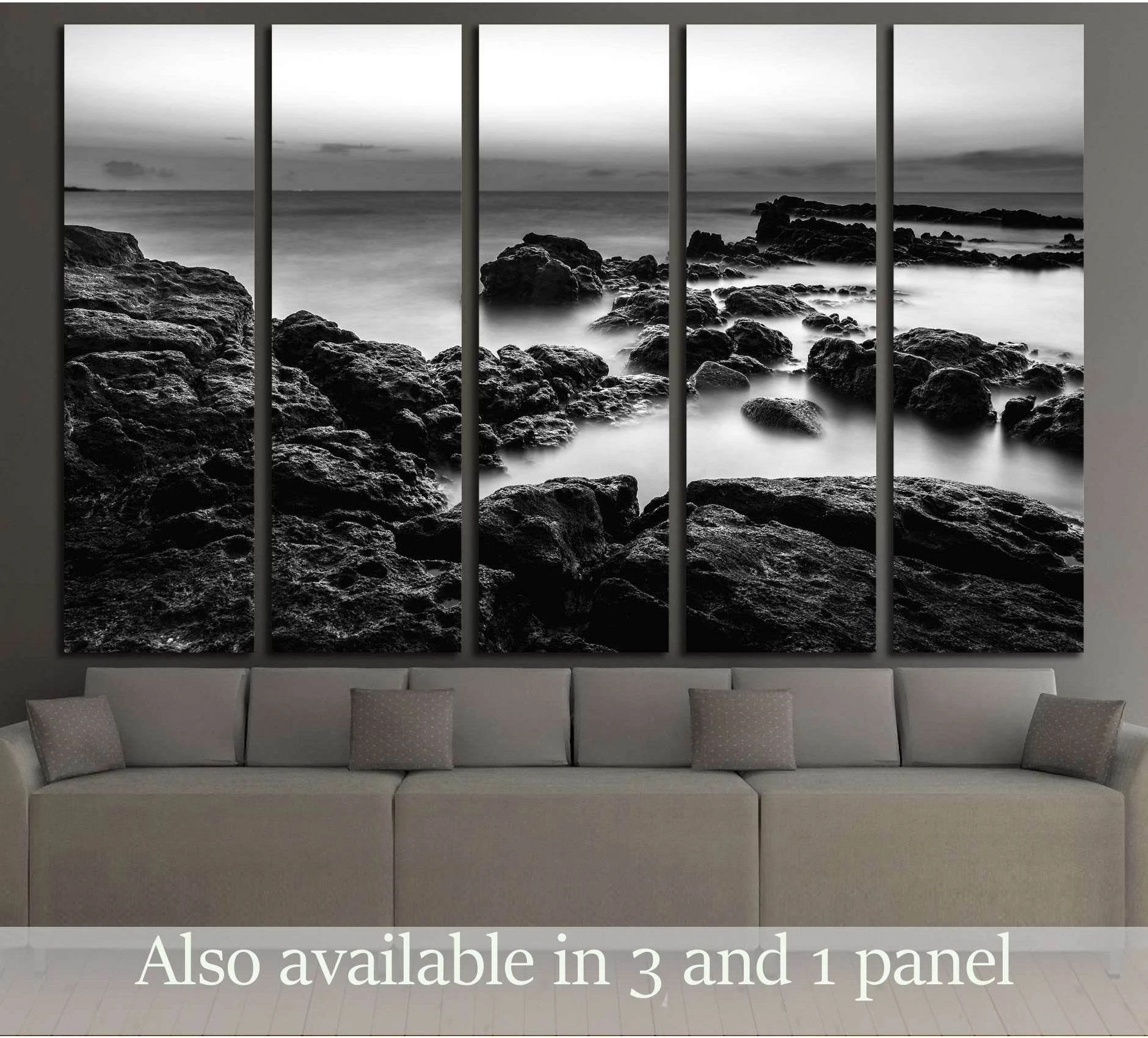 Black and white rocky seascape canvas print above a sofa in a modern living room