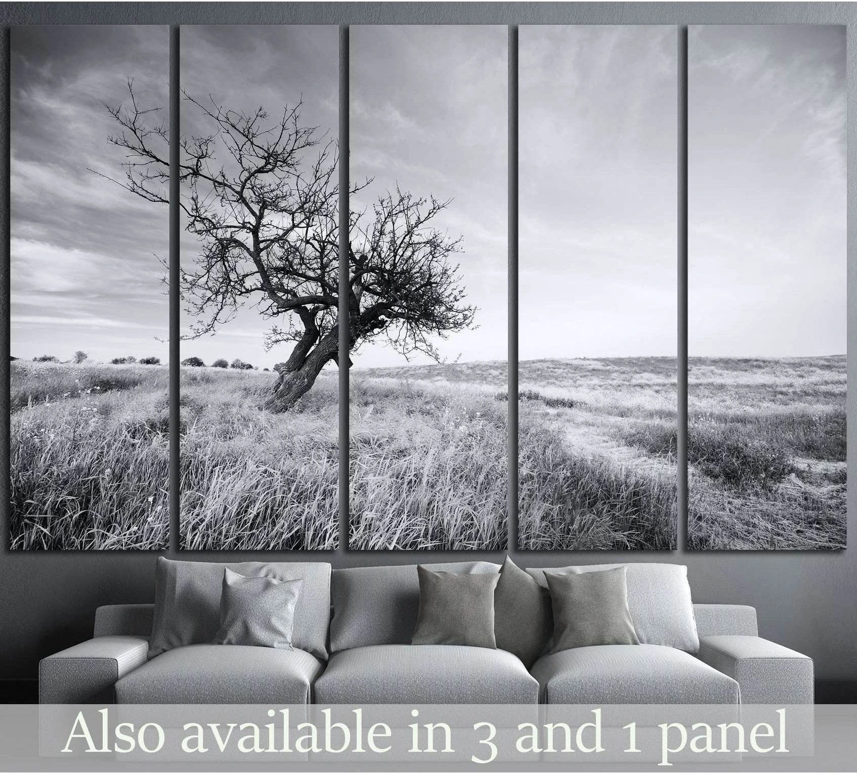 Black and white lone tree canvas print in an open grassy field, displayed above a sofa in a modern living room