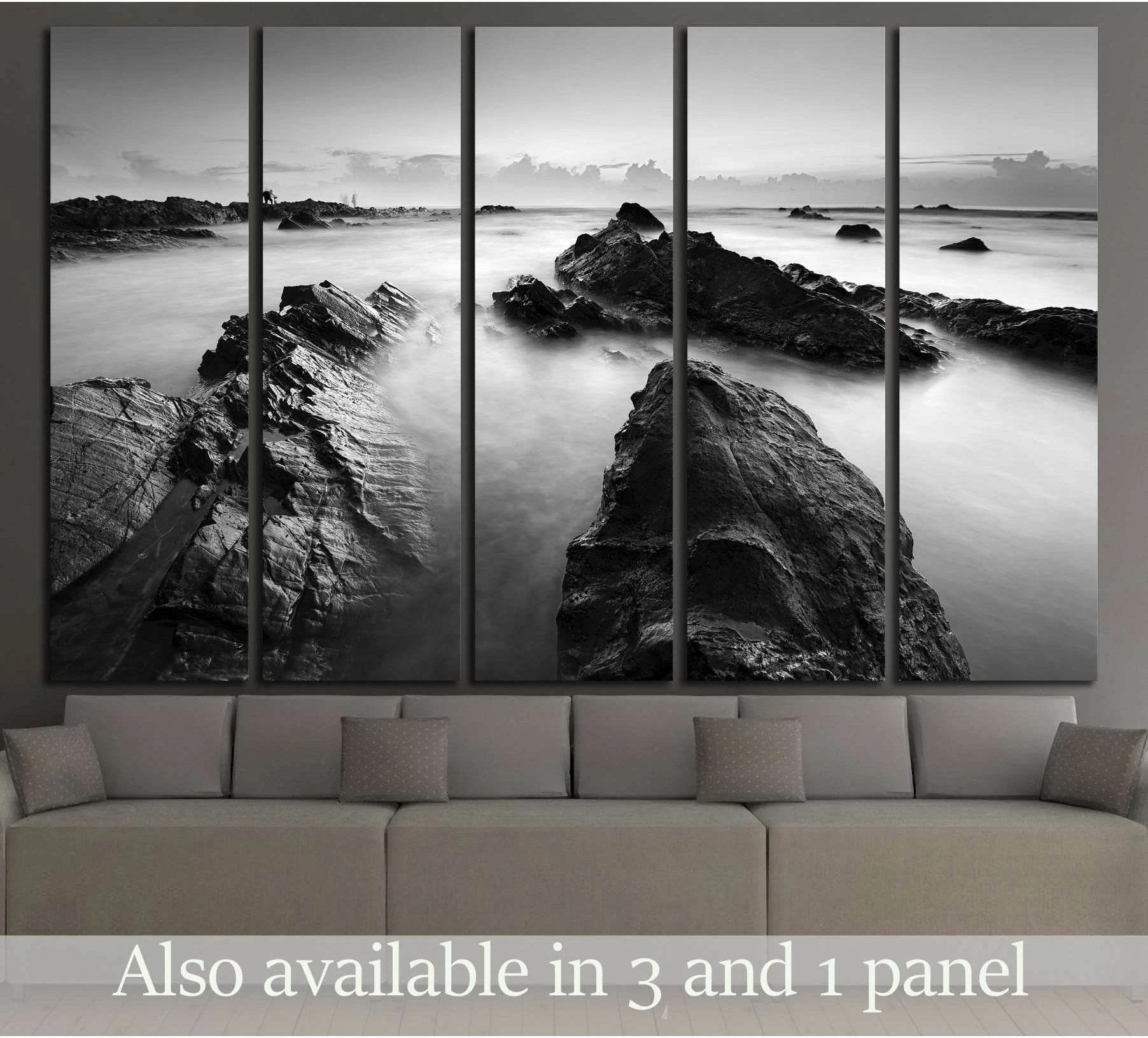 Black and white long exposure seascape canvas print with rocky shoreline above a sofa in a modern living room