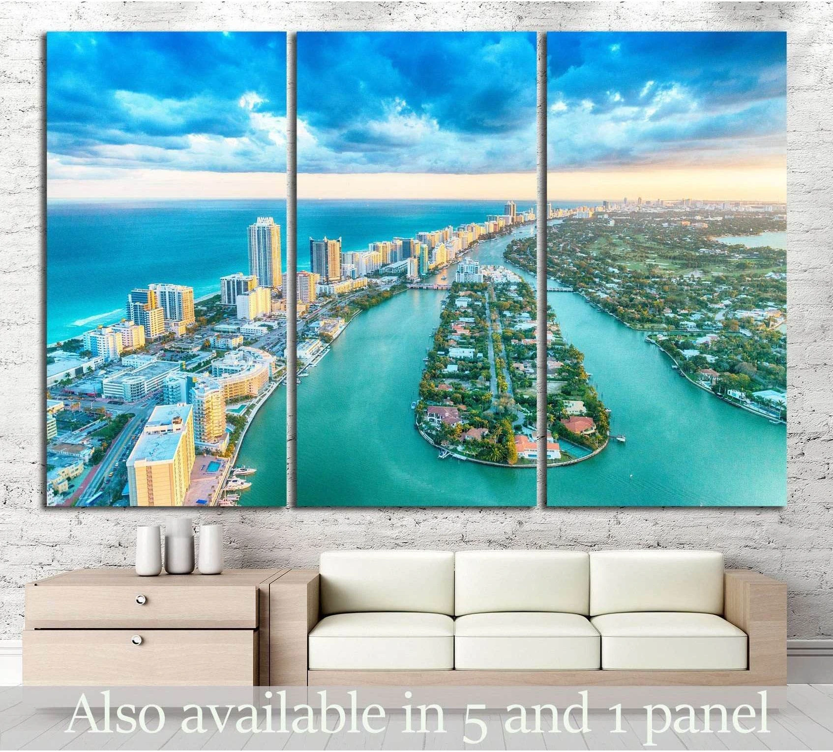 Panoramic Miami Beach aerial canvas print in triptych panels above a sofa in a coastal living room