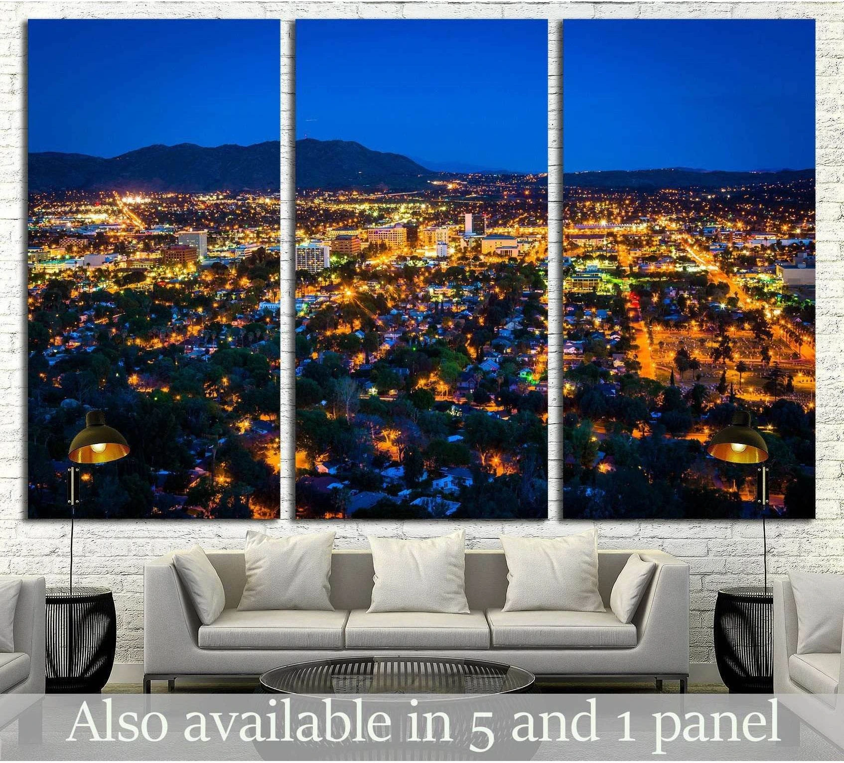 Riverside skyline triptych canvas print above a sofa with glowing city lights at dusk