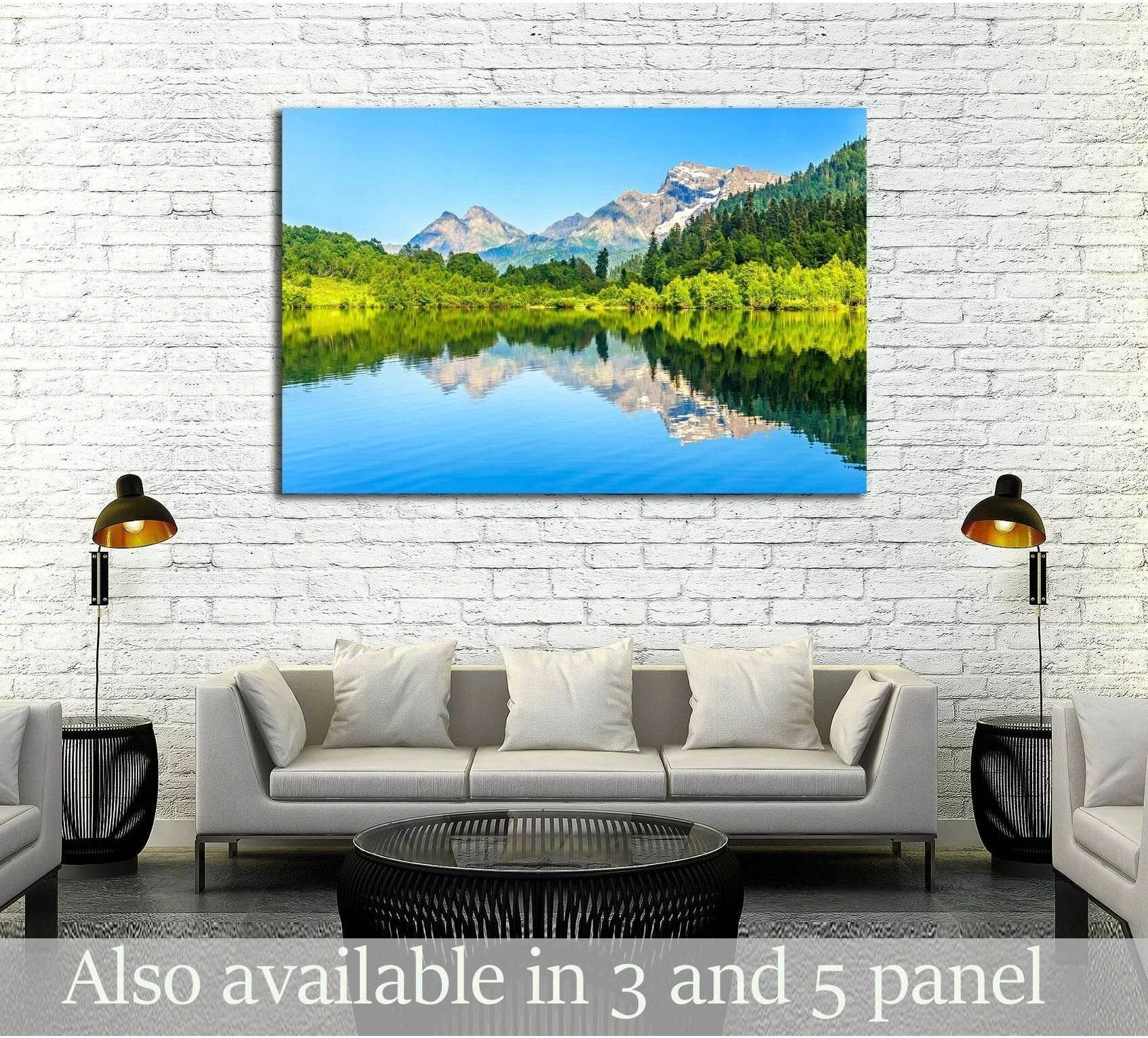 Mountain lake canvas print with alpine peaks, green forest reflection, hung above sofa in modern living room