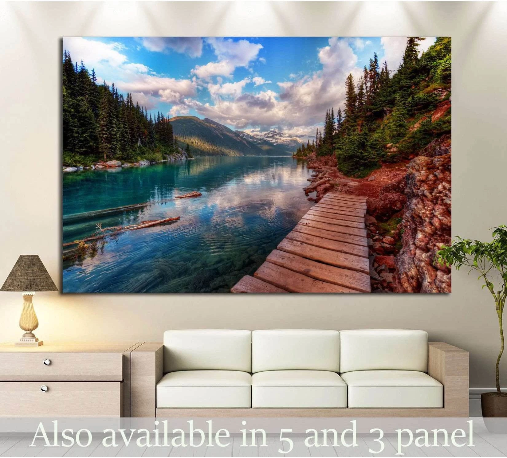 Mountain lake canvas print with turquoise water, evergreen trees, and boardwalk above sofa