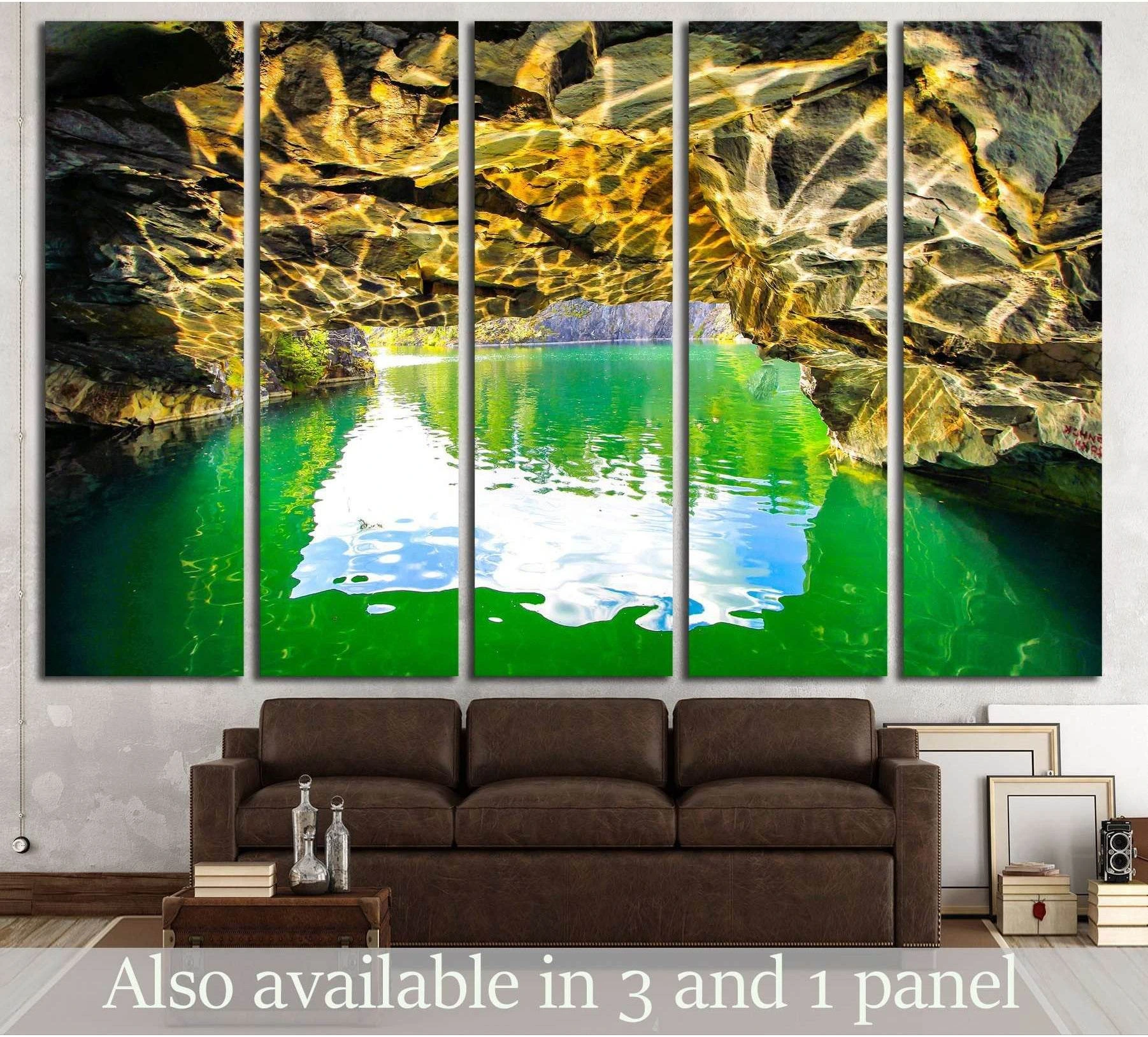 Mountain cave canvas print with emerald lake water and golden rock reflections, hung above a brown sofa