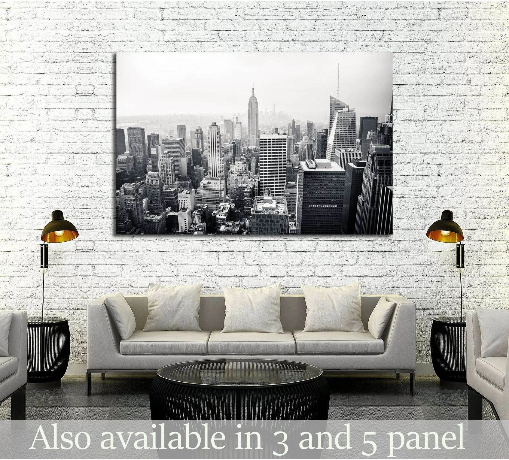 Black and white New York City aerial canvas print displayed above a sofa in a modern living room