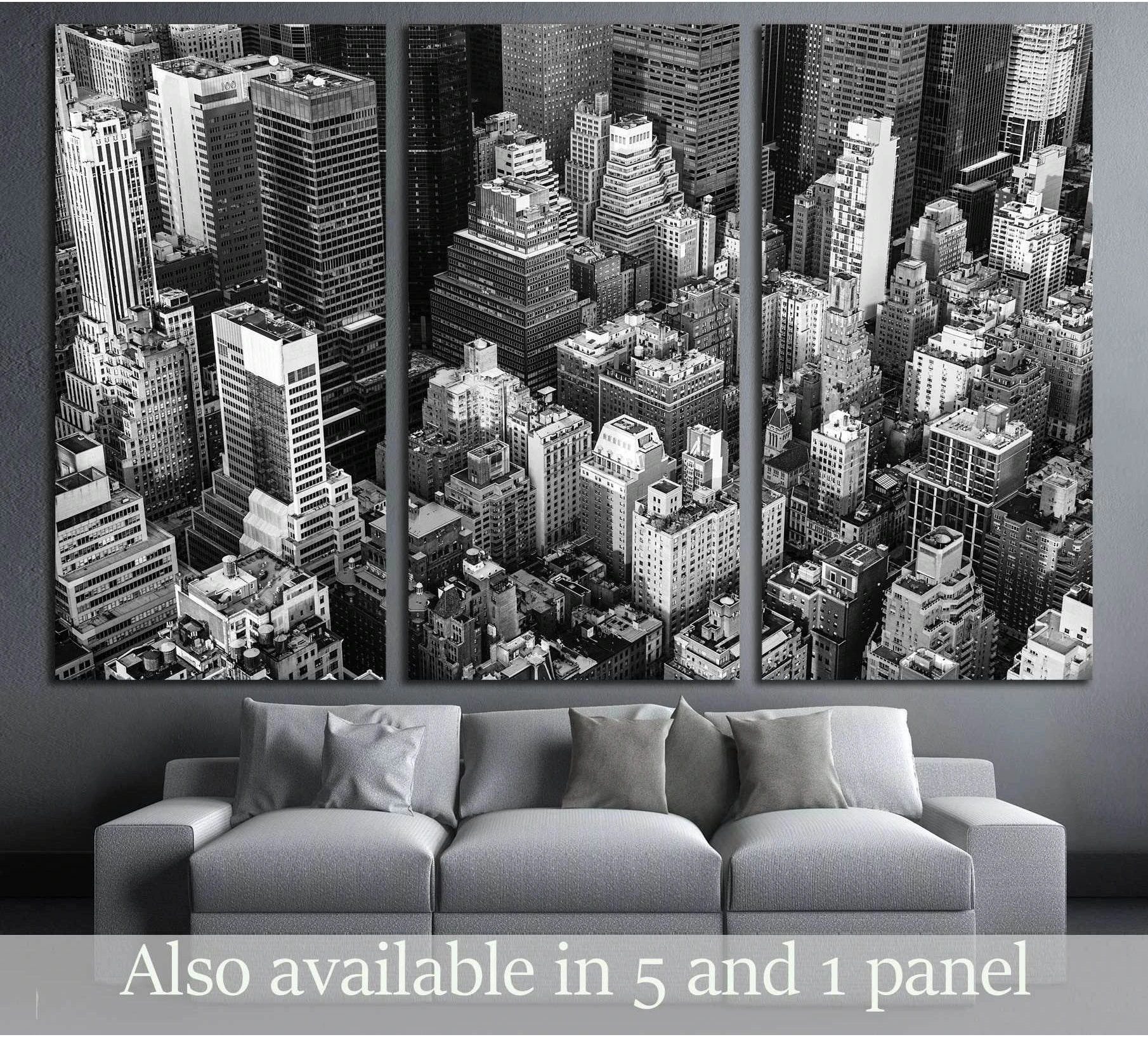 Black and white Manhattan aerial canvas print with dense NYC skyscrapers above a gray sofa