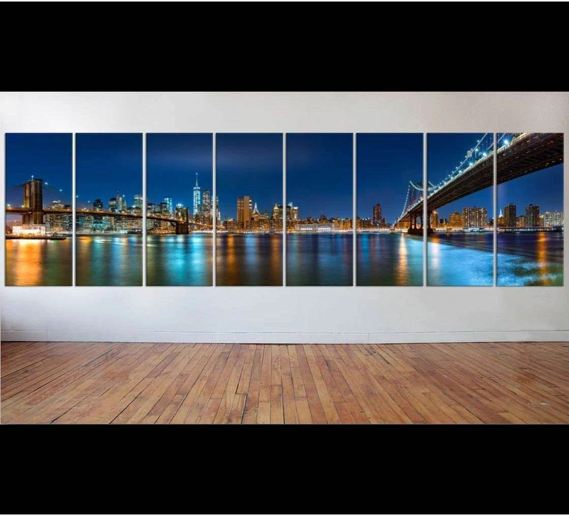 Multi-panel New York City night panorama canvas print with illuminated bridges and blue skyline above a wooden floor