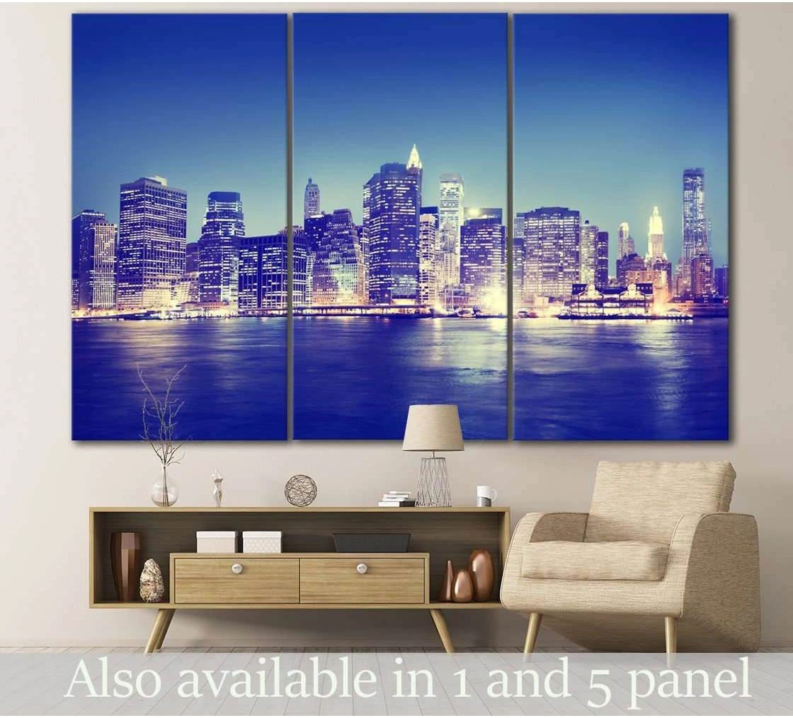 Blue NYC skyline triptych canvas print with Manhattan at night above a console in a modern living room