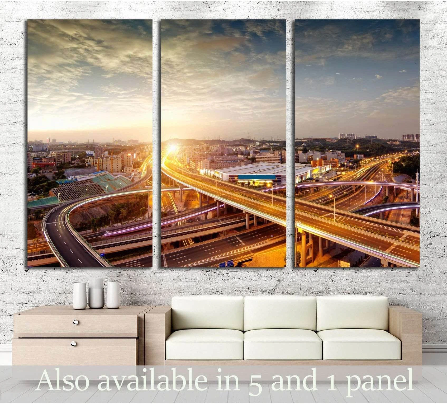 Triptych bridge cityscape canvas print with glowing highway lights above a sofa