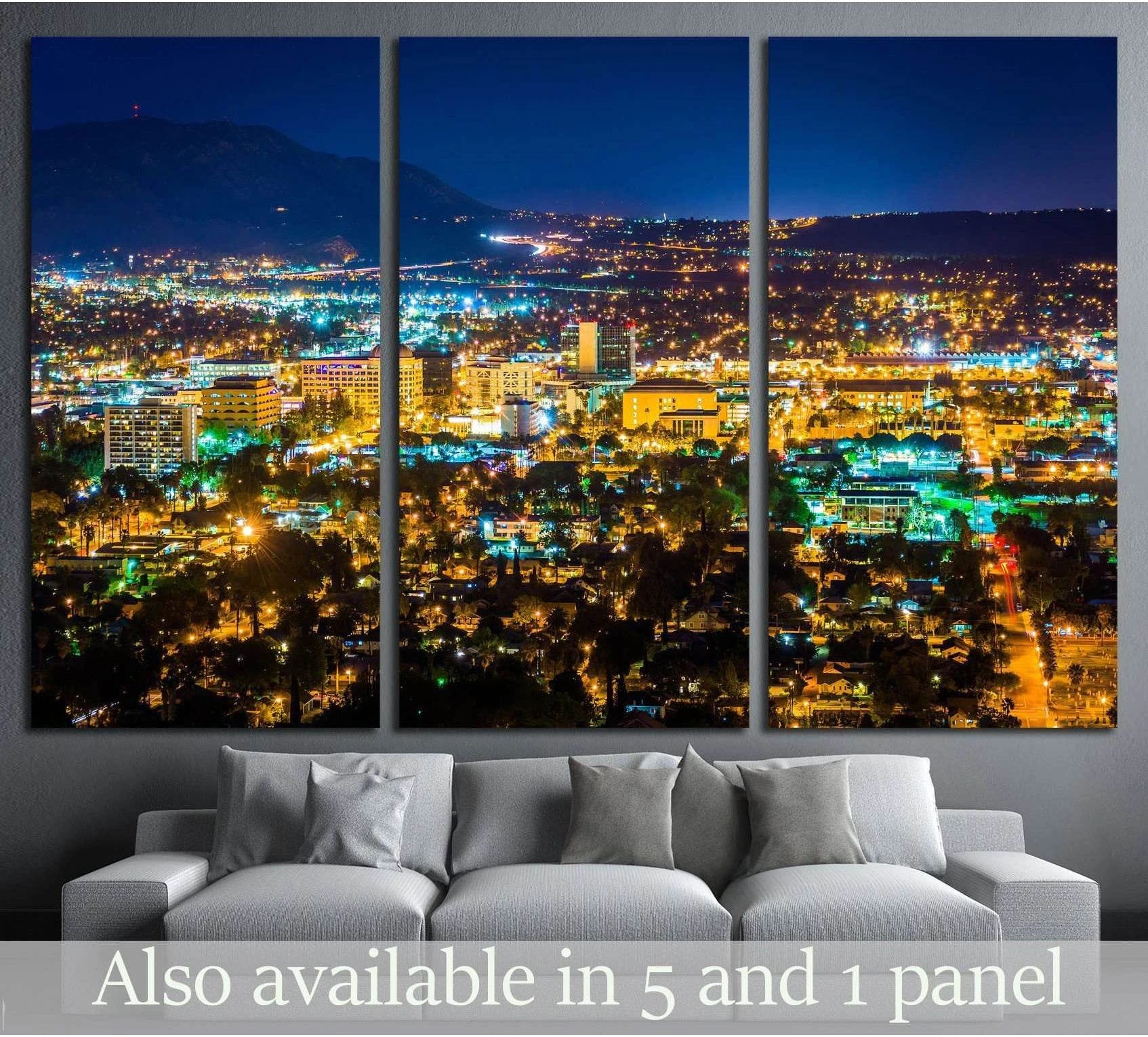 Riverside night skyline triptych canvas print above sofa with glowing city lights and mountain backdrop