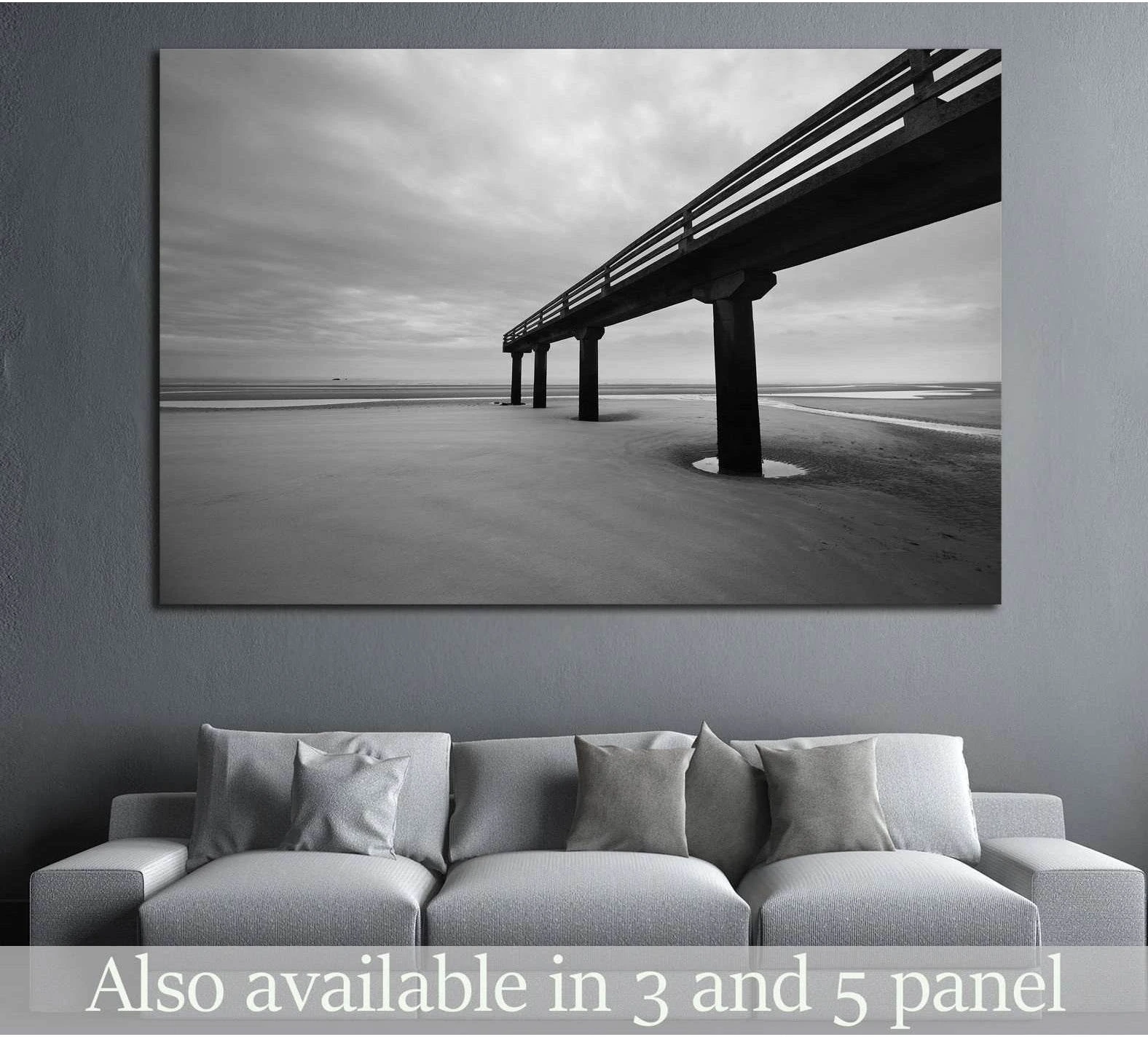 Black and white Omaha Beach pier canvas print hung above a sofa in a modern gray living room
